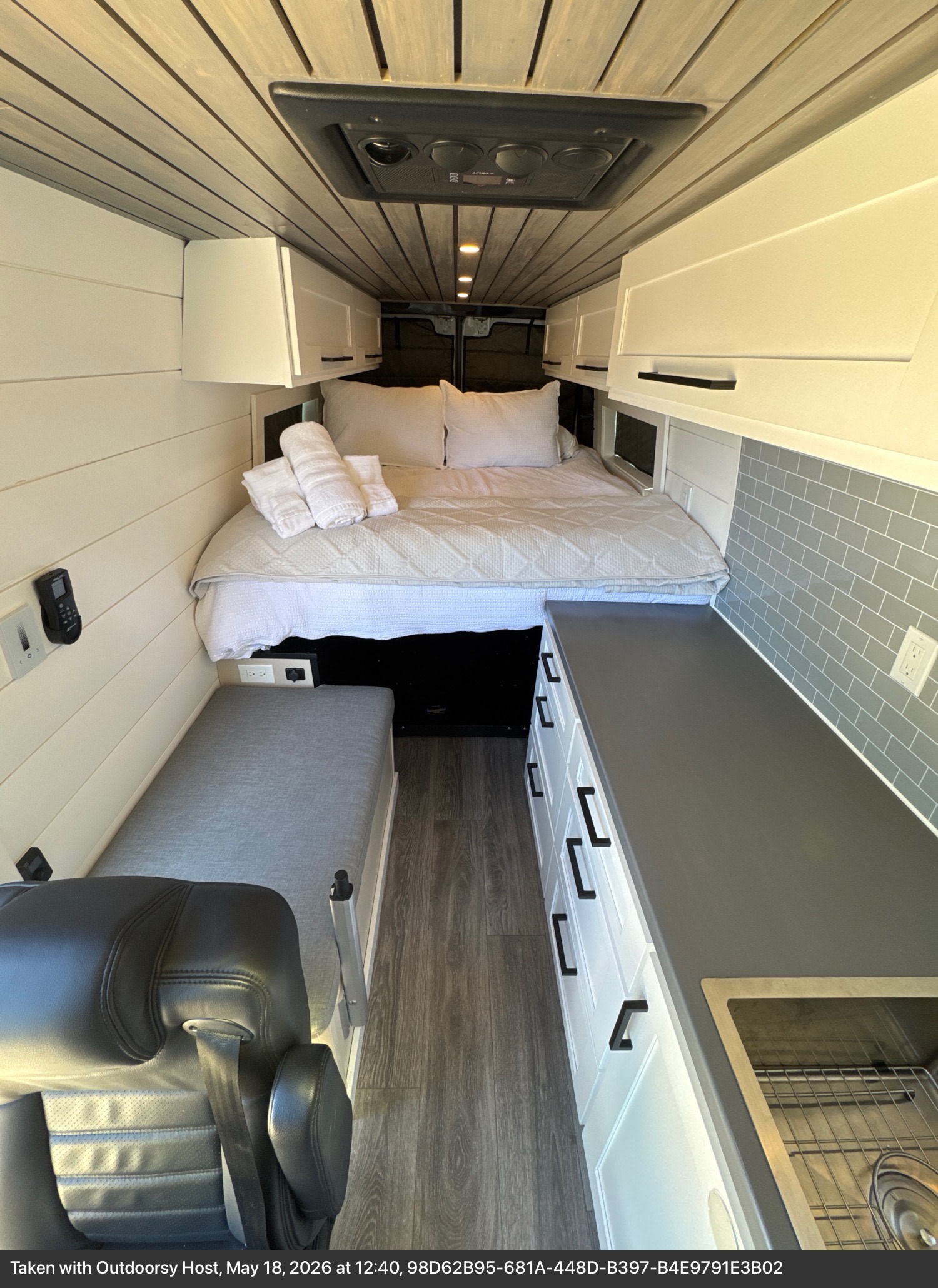 Modern RV rental interior: a comfy bed, functional kitchen with sink, sleek cabinets, and cozy bench seating.. Mercedes-Benz Sprinter RV Motorhome Campervan 2012