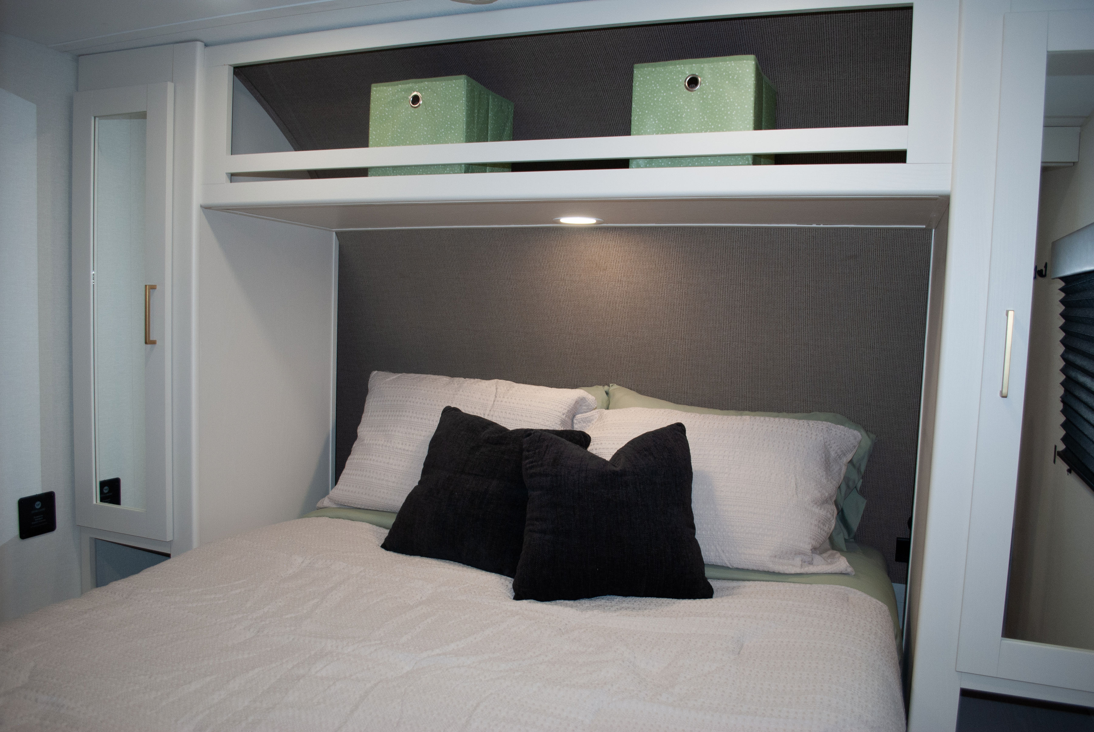 RV rental bedroom: a cozy bed with an upholstered headboard, practical overhead storage, and recessed lighting.. Grand Design Transcend Xplor 2026