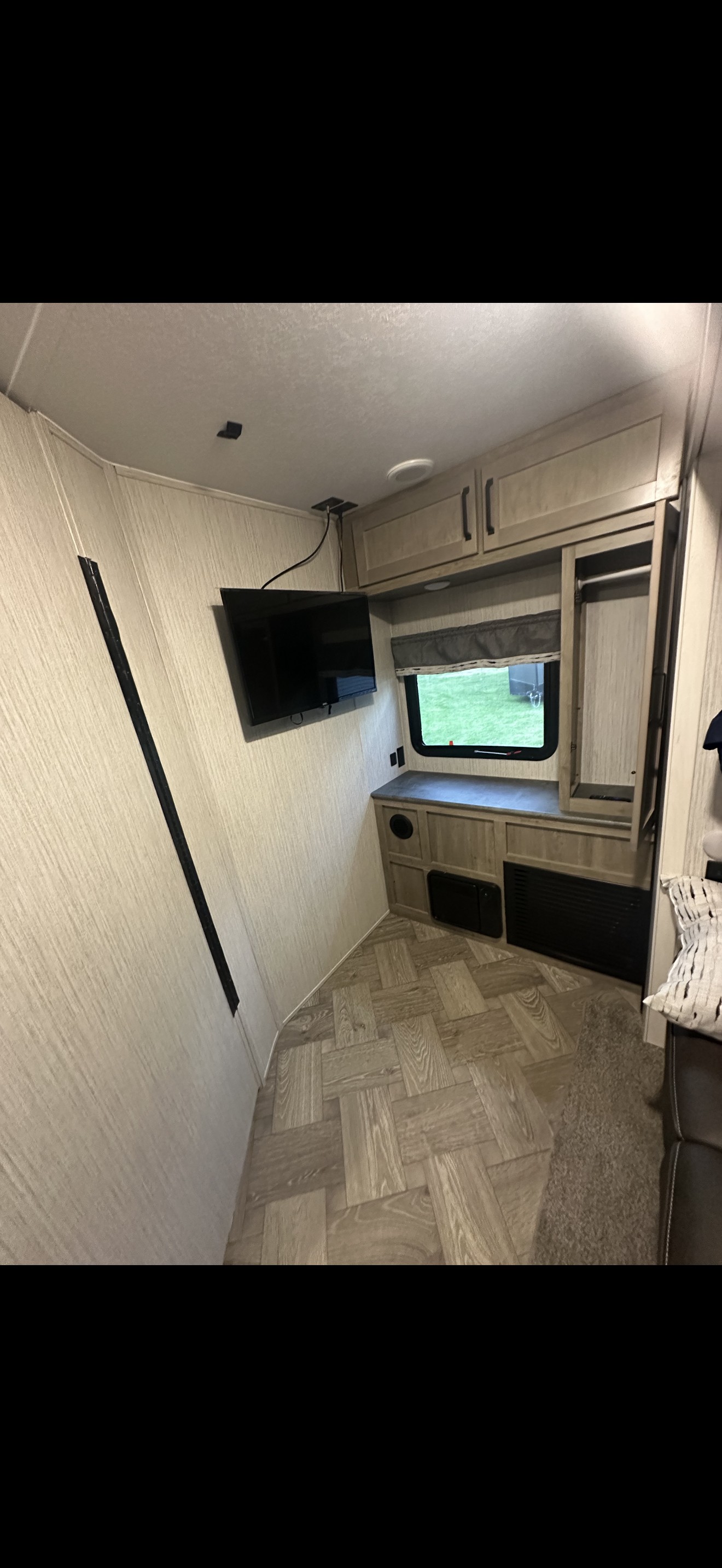 Inviting RV rental interior: wood-look walls, herringbone floor, wall-mounted TV, cabinets, & window. Perfect camper.. Forest River Palomino Puma 2022