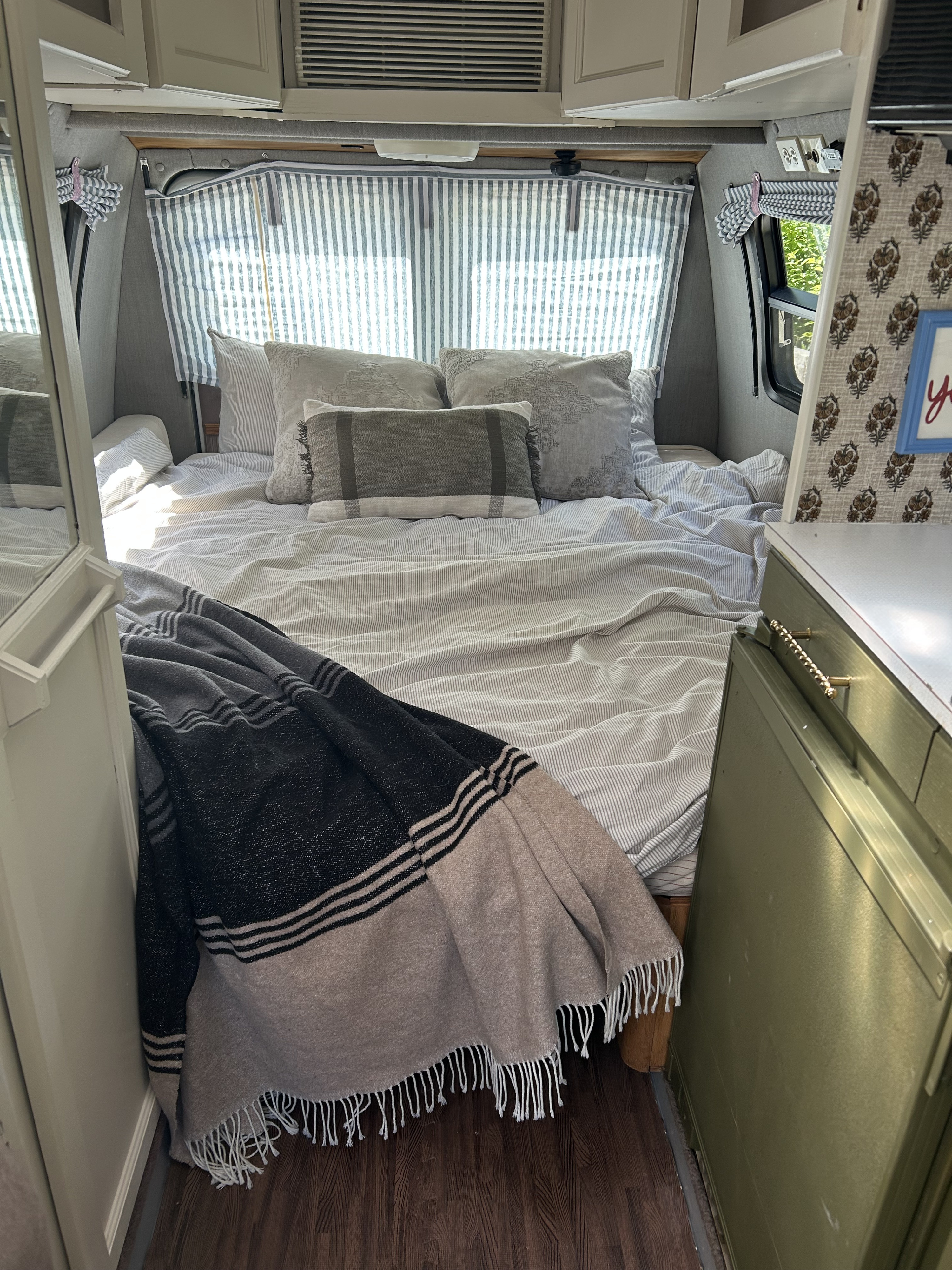 Cozy RV rental bedroom with striped bedding, fluffy pillows, and a comfy throw blanket, ideal for a relaxing getaway.. Roadtrek 190 Popular 1995