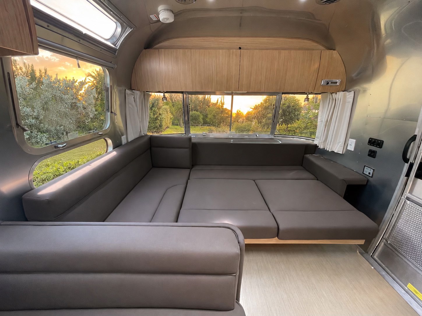 Modern Airstream RV rental interior with convertible seating and a beautiful sunset view.. Airstream Flying Cloud 2019