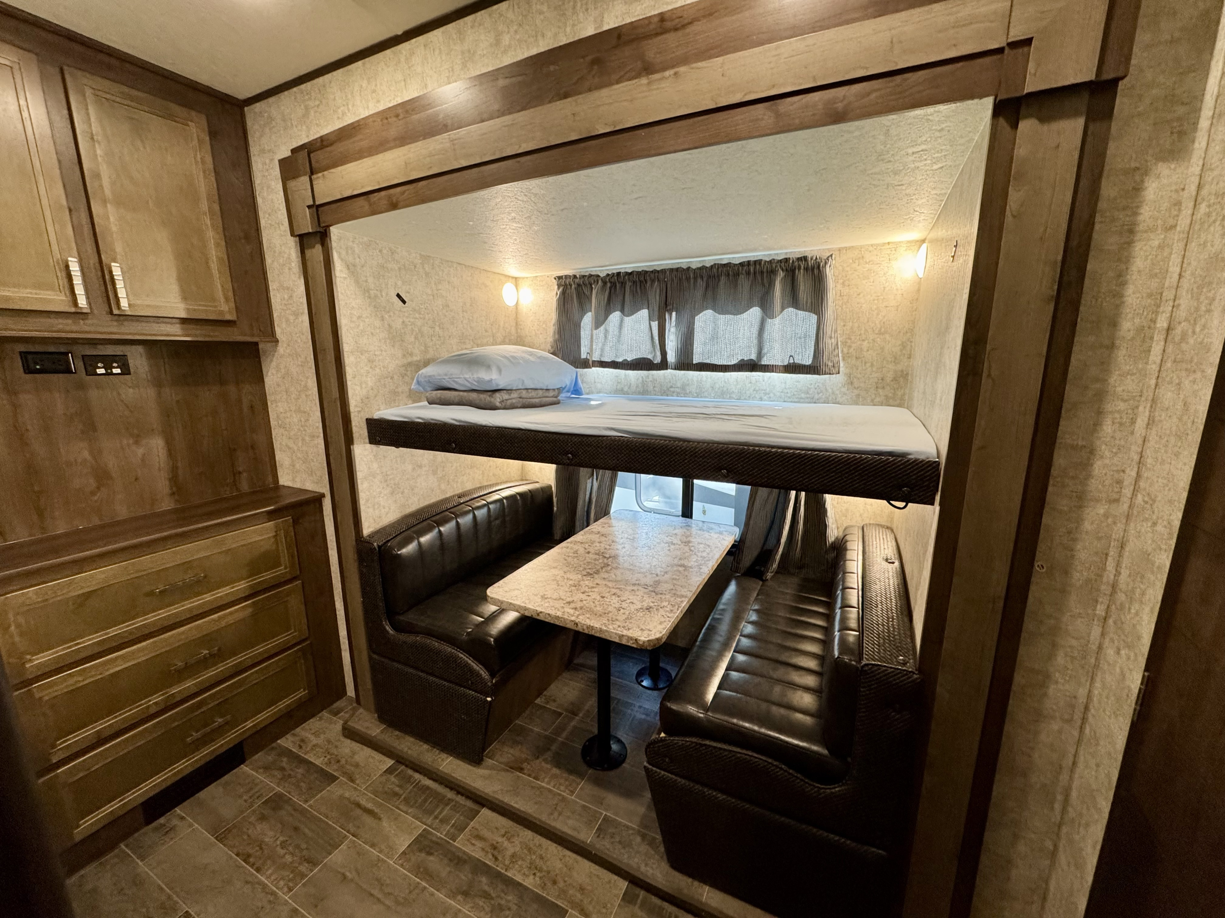 Cozy RV rental interior with a bunk bed above a dinette seating area, wood cabinets, and tiled floor.. Highland Ridge RV Mesa Ridge 2018