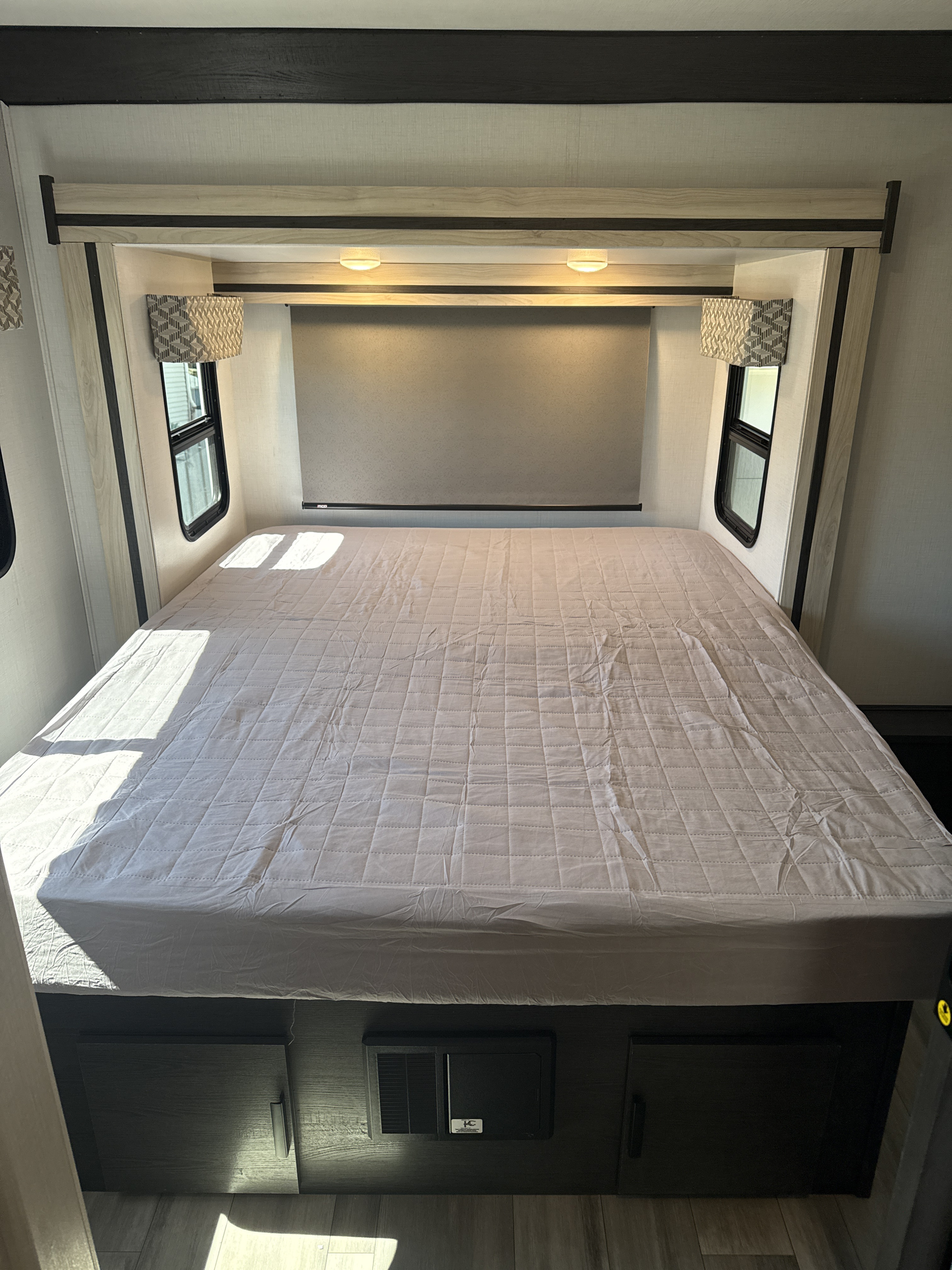 RV rental bedroom: a large bed with quilted mattress, side windows, overhead lights, and under-bed storage. Sunlight filters in.. Forester 2501CD 2023