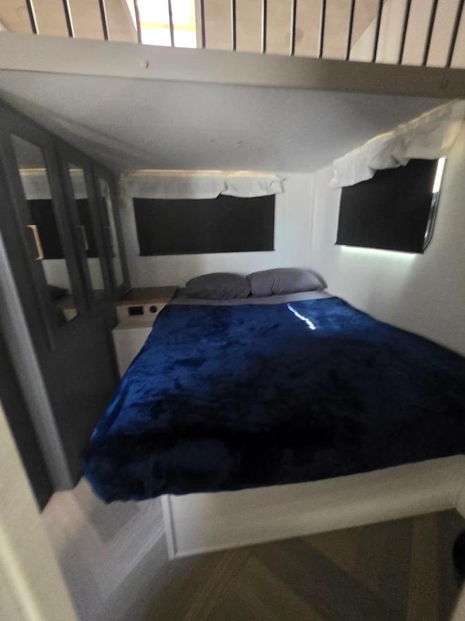 Cozy rv rental bedroom showing a blue-covered bed, dual windows with black blinds, and a mirrored closet.. Crusader Crusader Fifth Wheel 2024