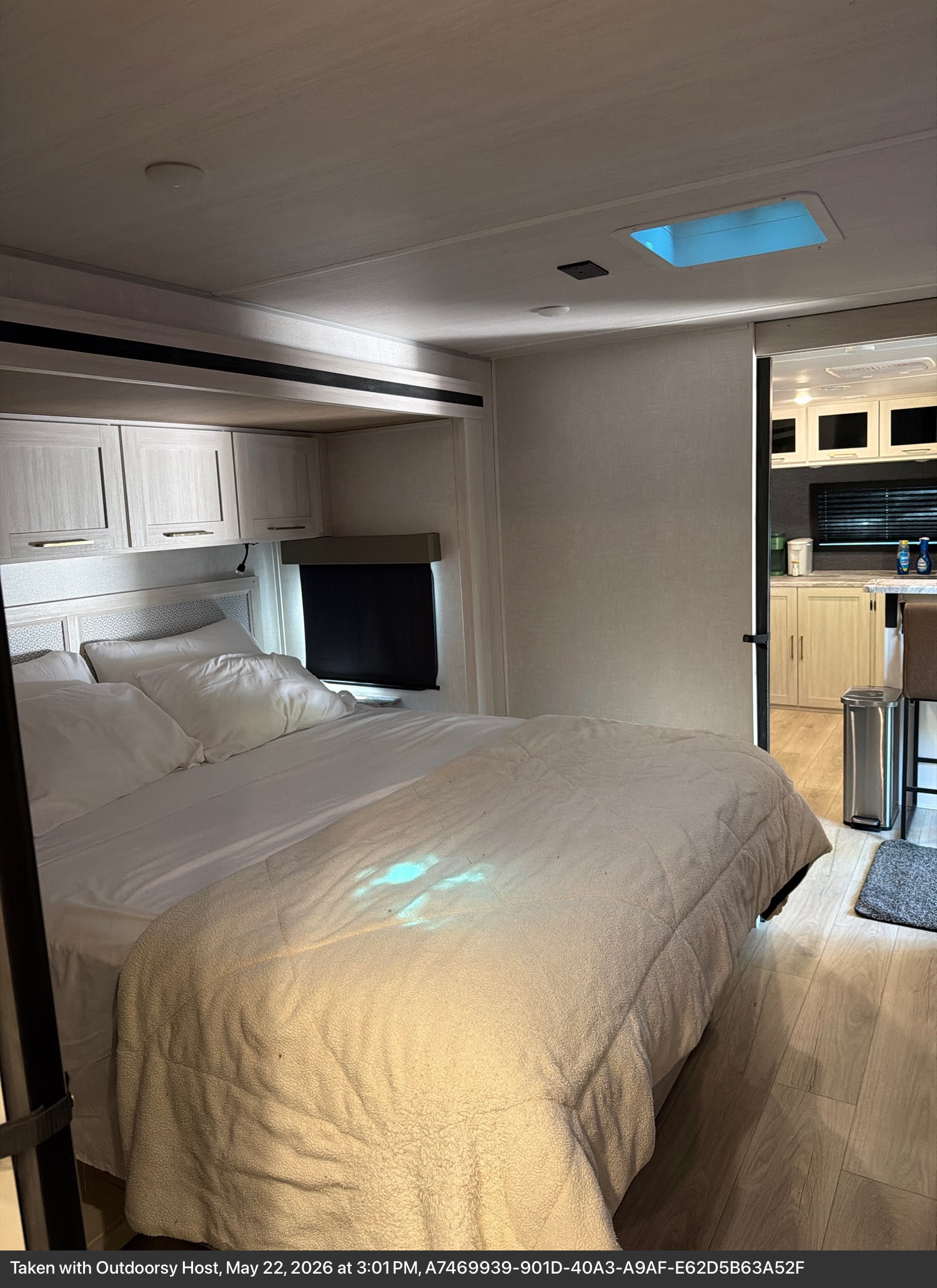 Cozy rv rental bedroom features a comfy bed, skylight, overhead cabinets, and a glimpse of the modern kitchen.. Forest River Surveyor Land Surveyor 2024