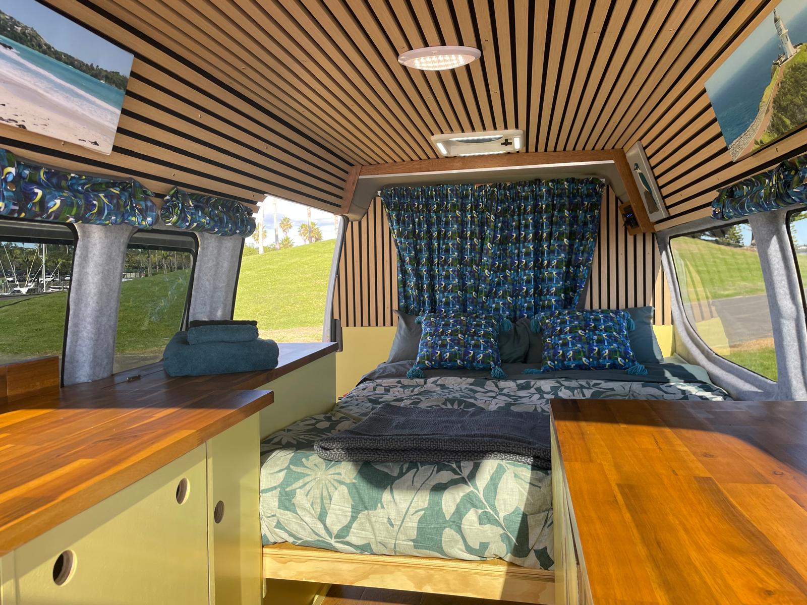 Cozy custom RV rental interior featuring a comfortable bed, wood accents, and scenic views for your next adventure.. Other Other 2019