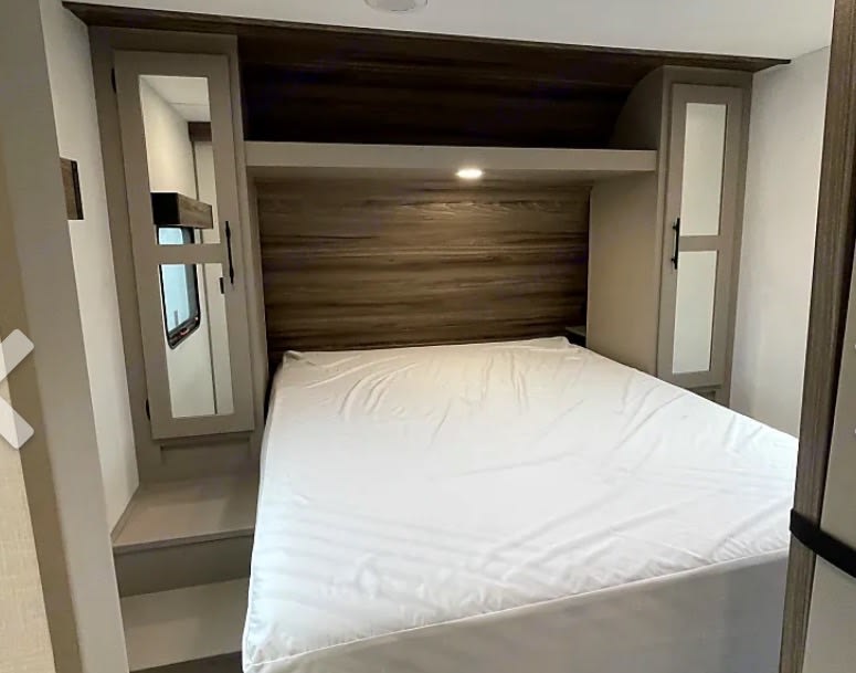 RV rental bedroom: a clean bed, wood-paneled headboard, and mirrored side cabinets in a compact space.. KZ Connect SE 2026