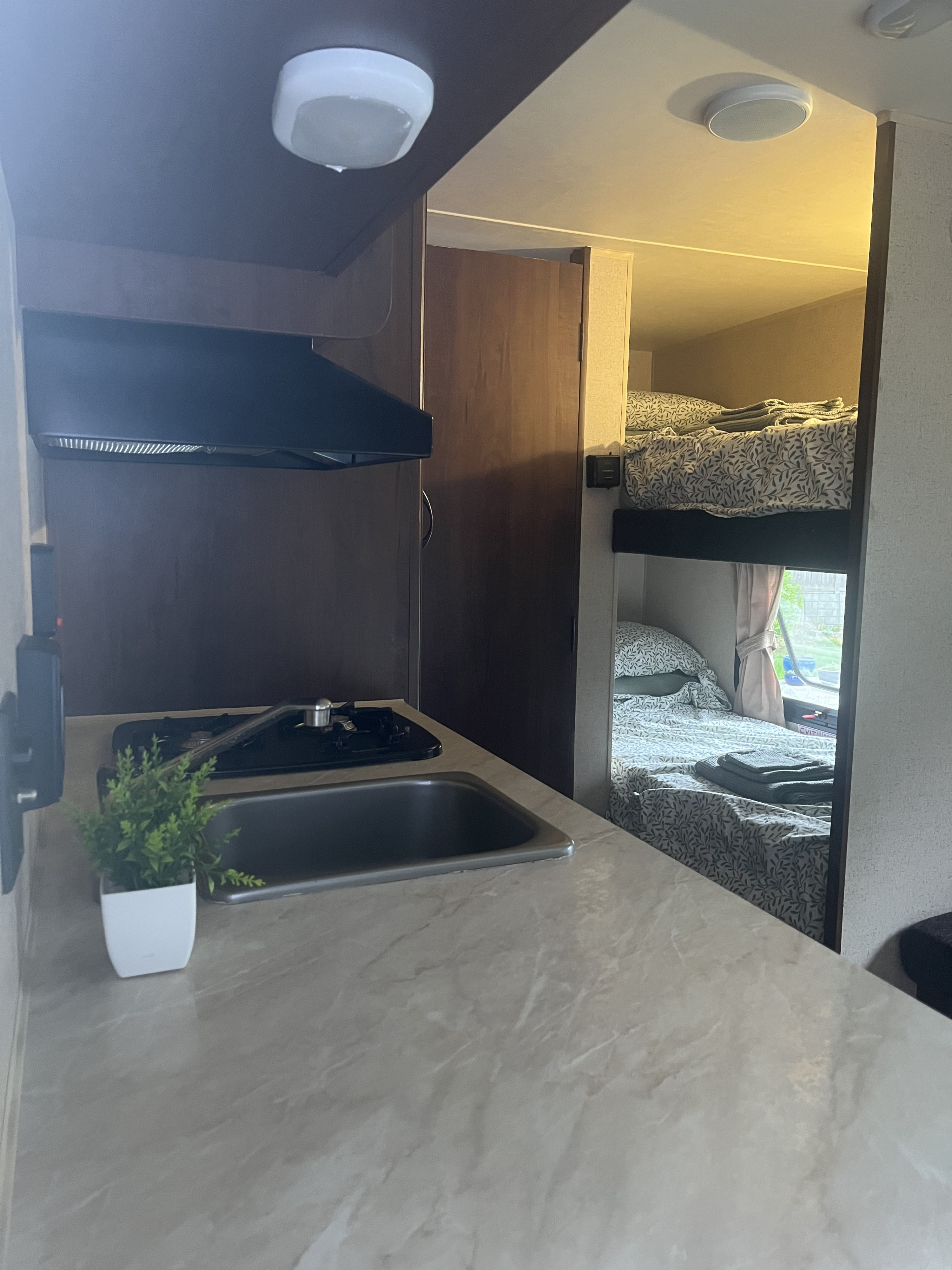 Cozy RV rental interior featuring a compact kitchen with stove and sink, plus comfortable bunk beds.. Jayco Jay Flight 2015