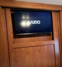 Built-in Vizio TV, recessed into wooden cabinetry, offers entertainment in this RV rental. Ideal for travel.. Forest River Salem Cruise Lite 2014