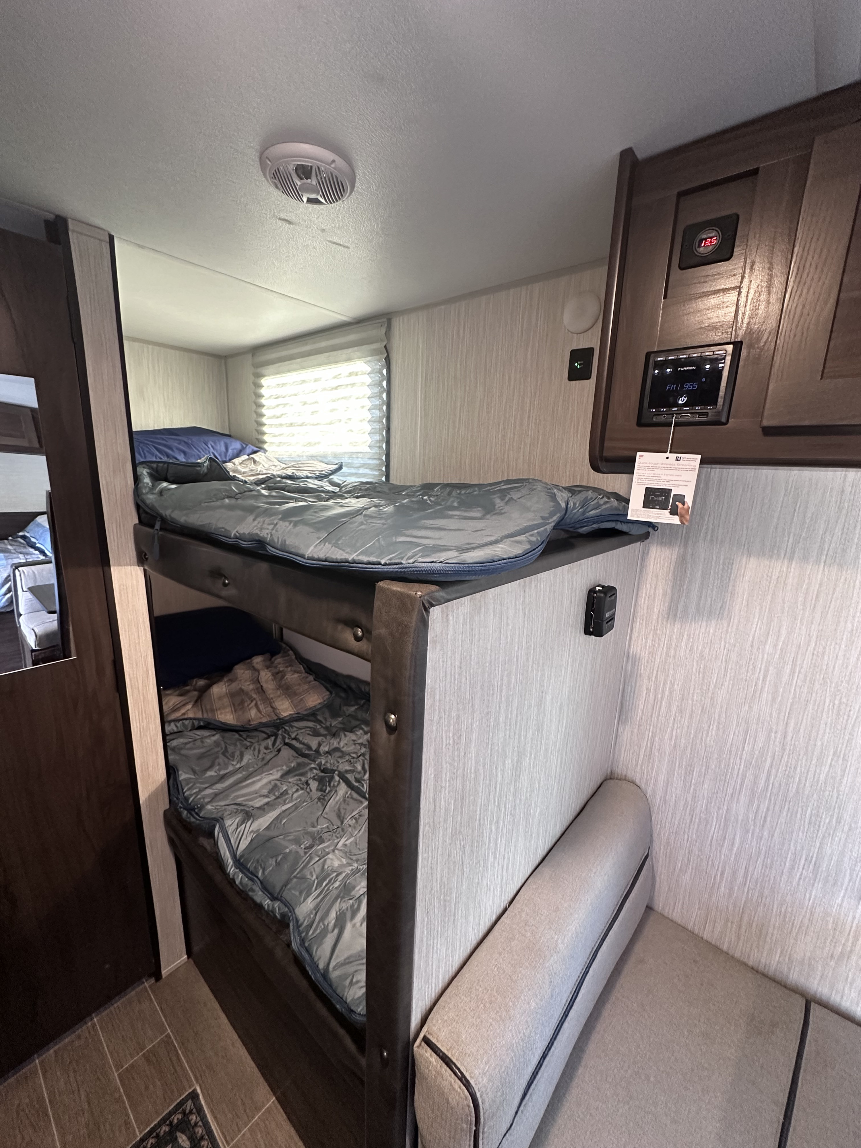 Cozy RV rental interior featuring bunk beds with sleeping bags, an integrated control panel, and a small dinette area for your adventure.. Forest River Cherokee Wolf Pup 2020