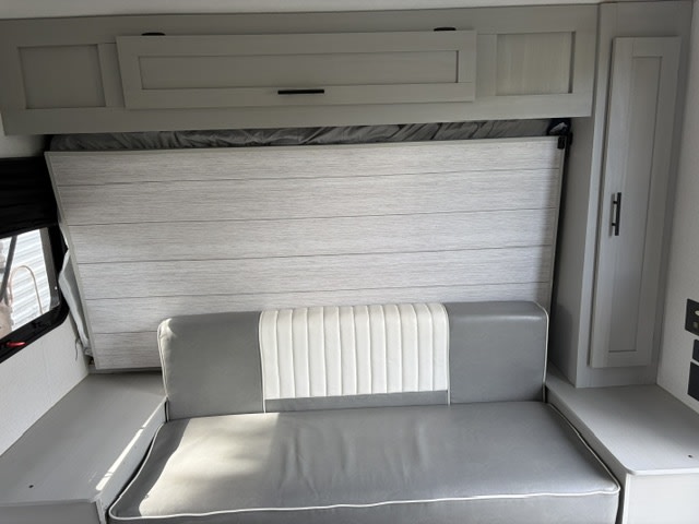 RV rental with a fold-down bed, comfortable sofa, and integrated storage cabinets for compact living.. Forest River Wildwood FSX 2022