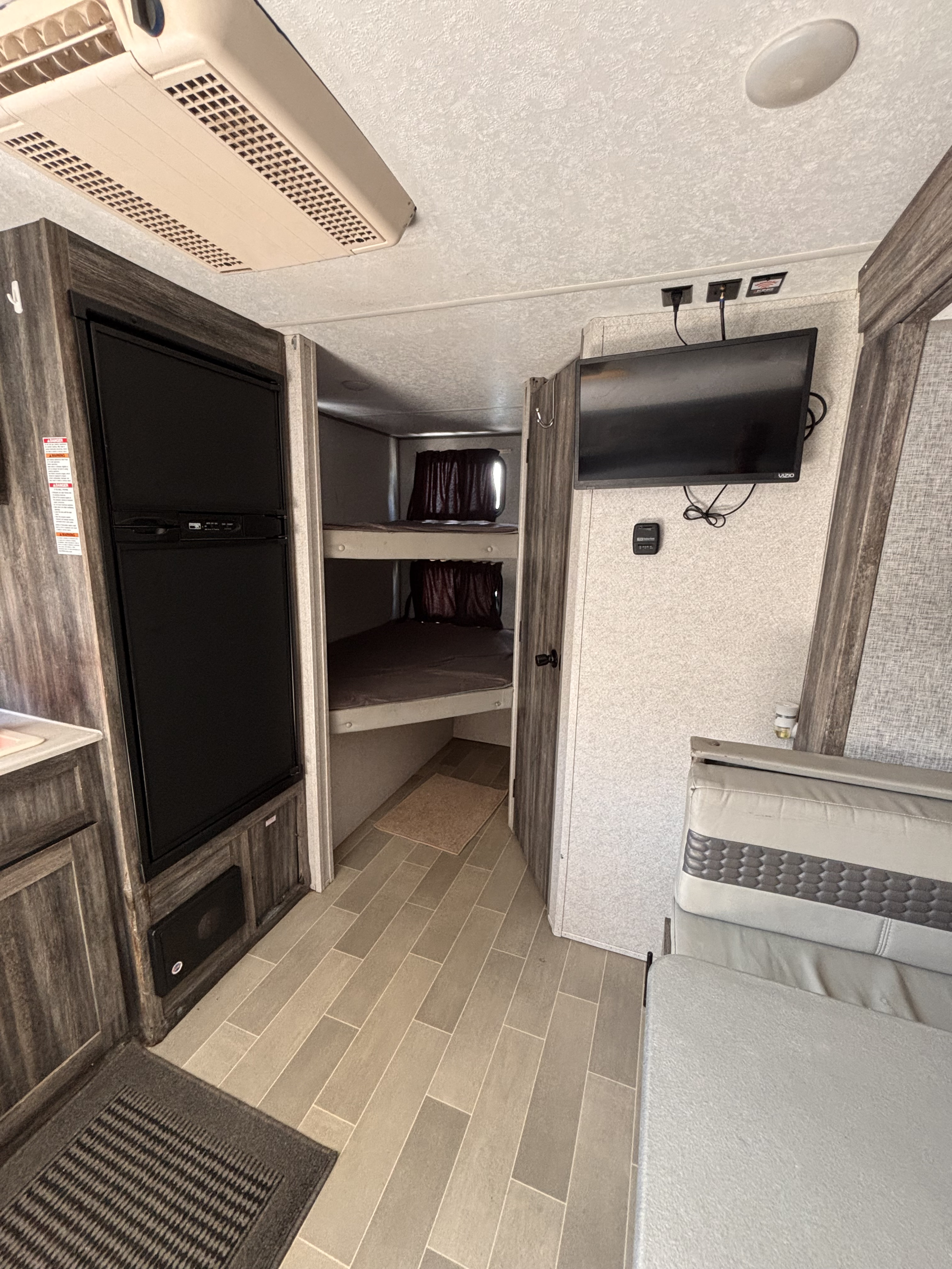RV rental interior featuring bunk beds, a refrigerator, TV, AC unit, and dinette seating area.. Forest River Salem FSX PLATINUM 2020