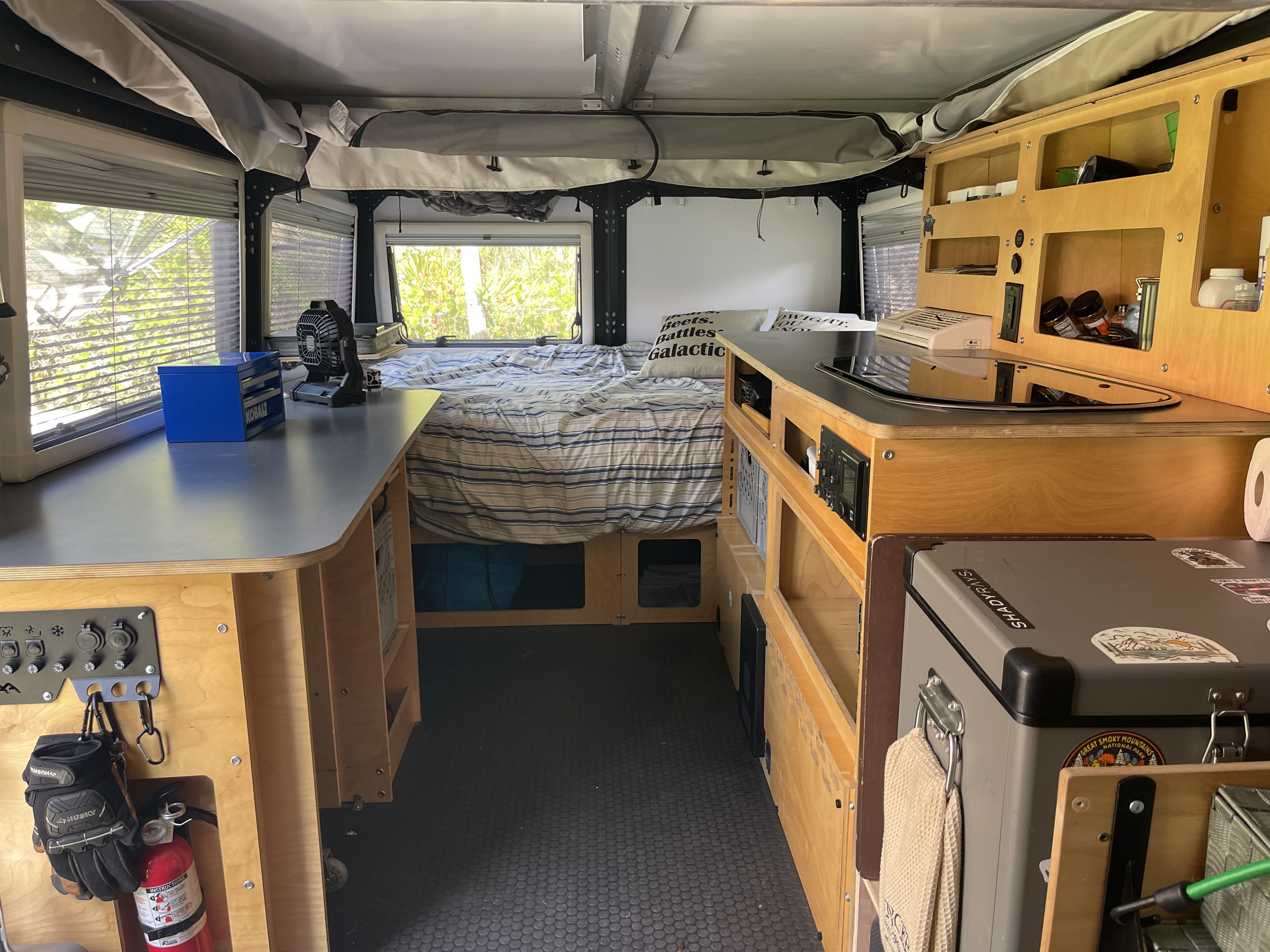 Explore this practical rv rental pop-top camper interior with a cozy bed, compact kitchen, and organized storage for your travels.. TAXA TAXA Trailer 2020
