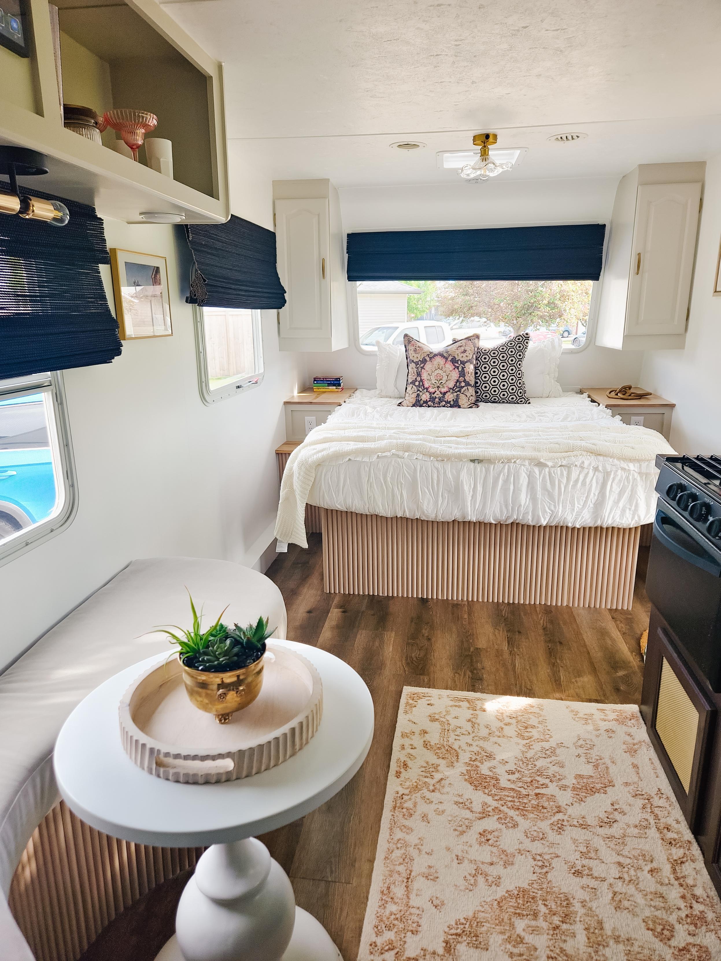 Experience this modern RV rental interior featuring a cozy bed, compact kitchen, and a small seating area with decorative elements.. Fleetwood Fleetwood Rockwood Lite 2501S 2007