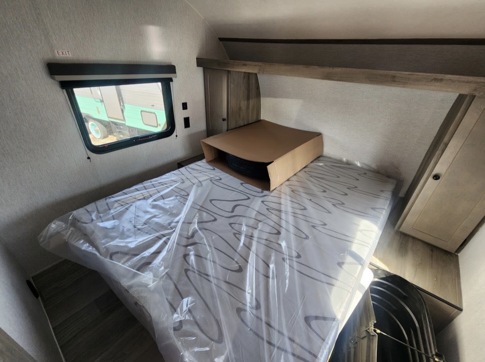 RV rental bedroom interior featuring a plastic-covered bed, exit window, and built-in storage, ready for adventure.. Sunset Park RV Sun Lite 2026