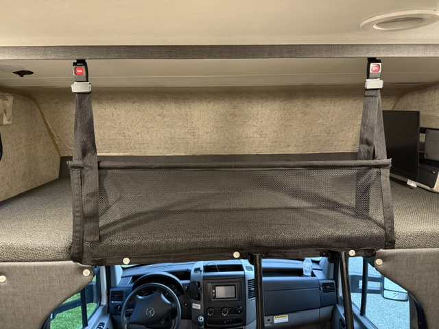 RV rental interior: Cab-over bunk bed with a safety net barrier, dashboard visible below.. Coachmen Prism 2150 2018