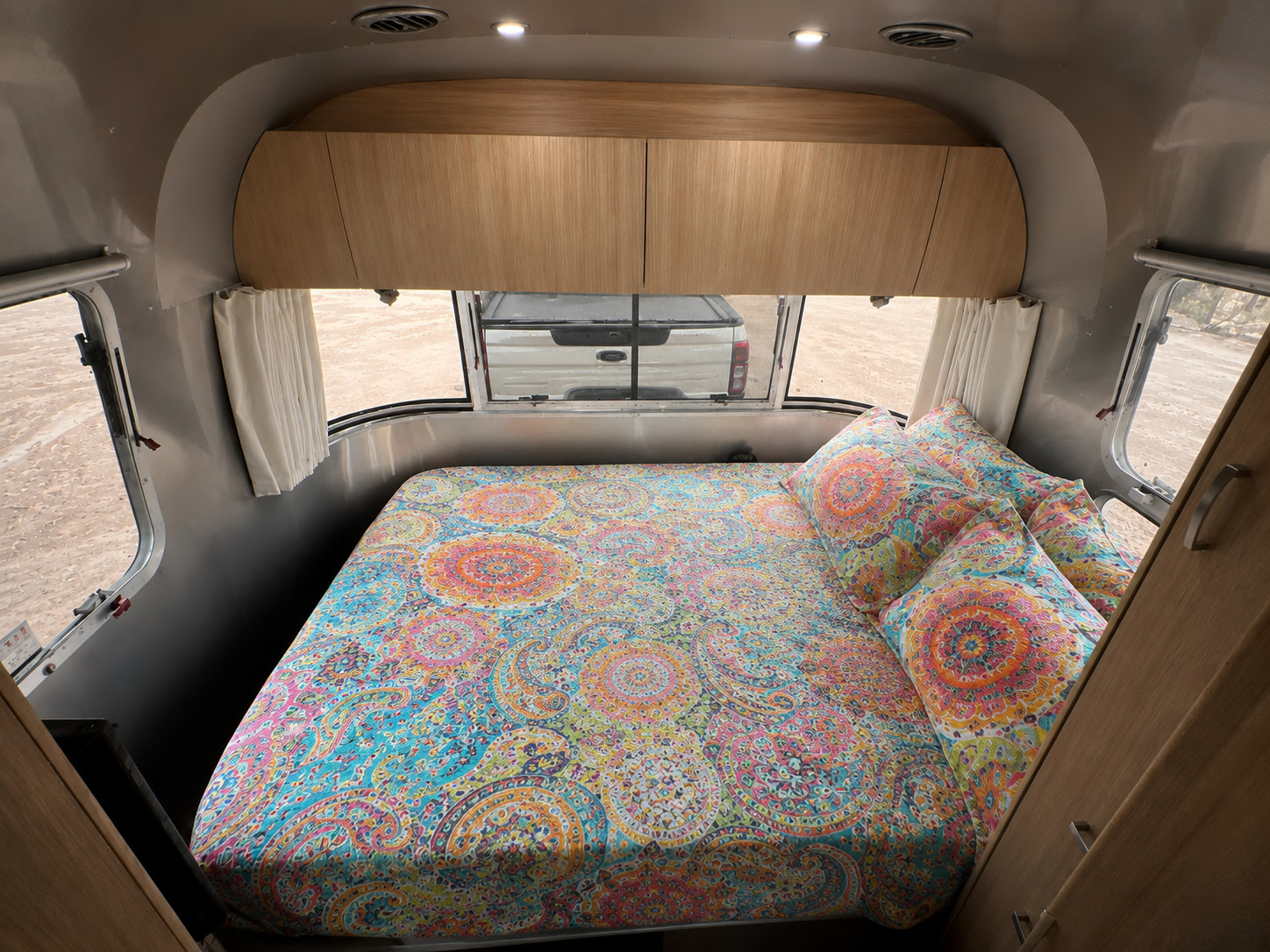 Vibrant RV rental bedroom: A comfortable bed with colorful paisley bedding inside a sleek metallic camper.. Airstream Flying Cloud 2018