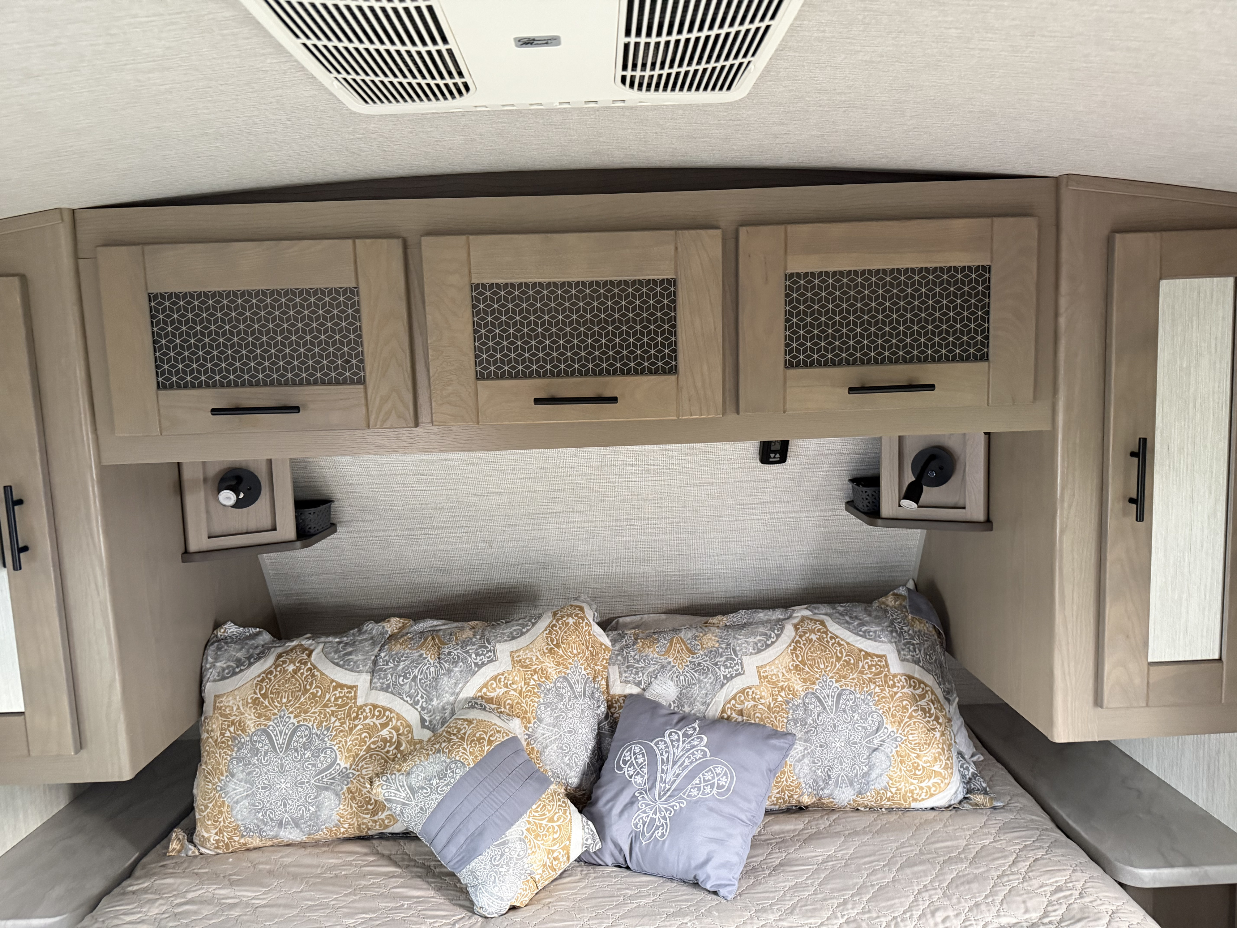 Cozy rv rental bedroom with overhead storage, patterned pillows, and Dometic AC for travel comfort.. Cruiser RV Twilight Signature 2021