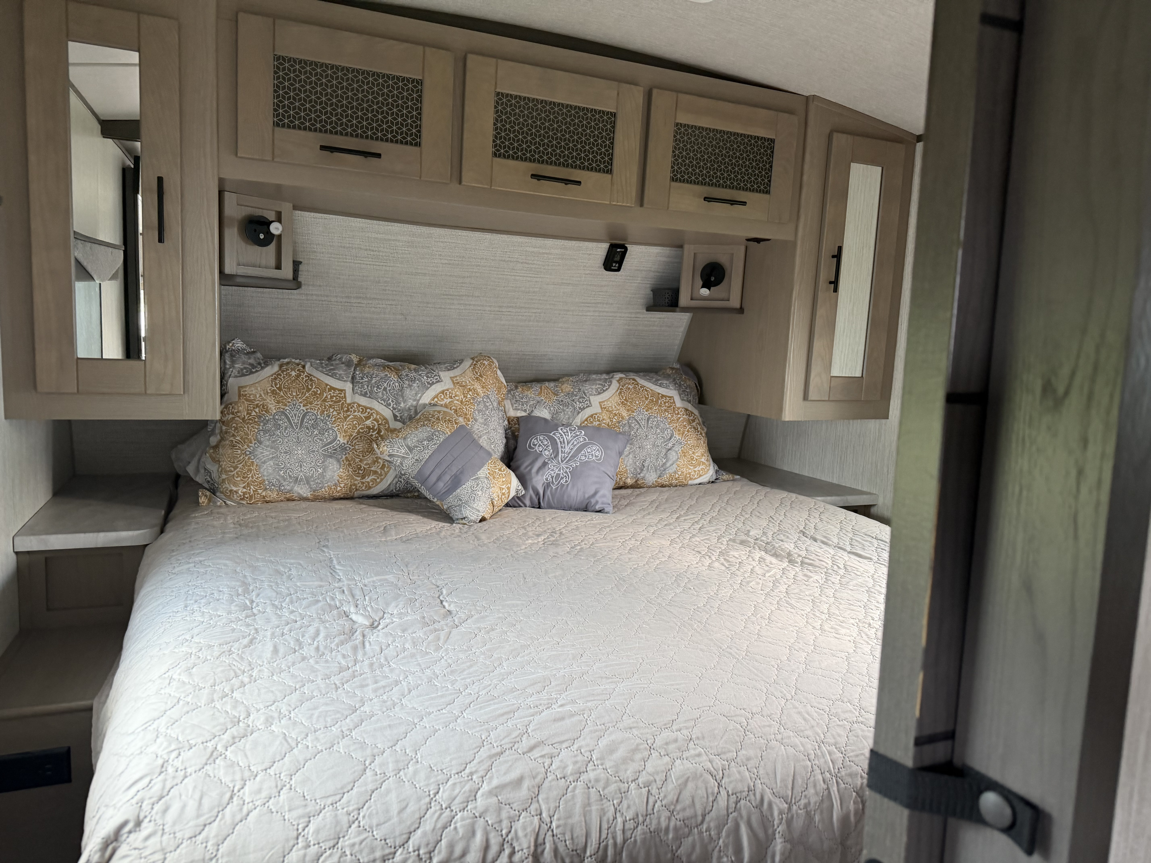 Cozy RV rental bedroom with a neatly made bed, decorative pillows, overhead storage, and reading lights for a comfortable stay.. Cruiser RV Twilight Signature 2021