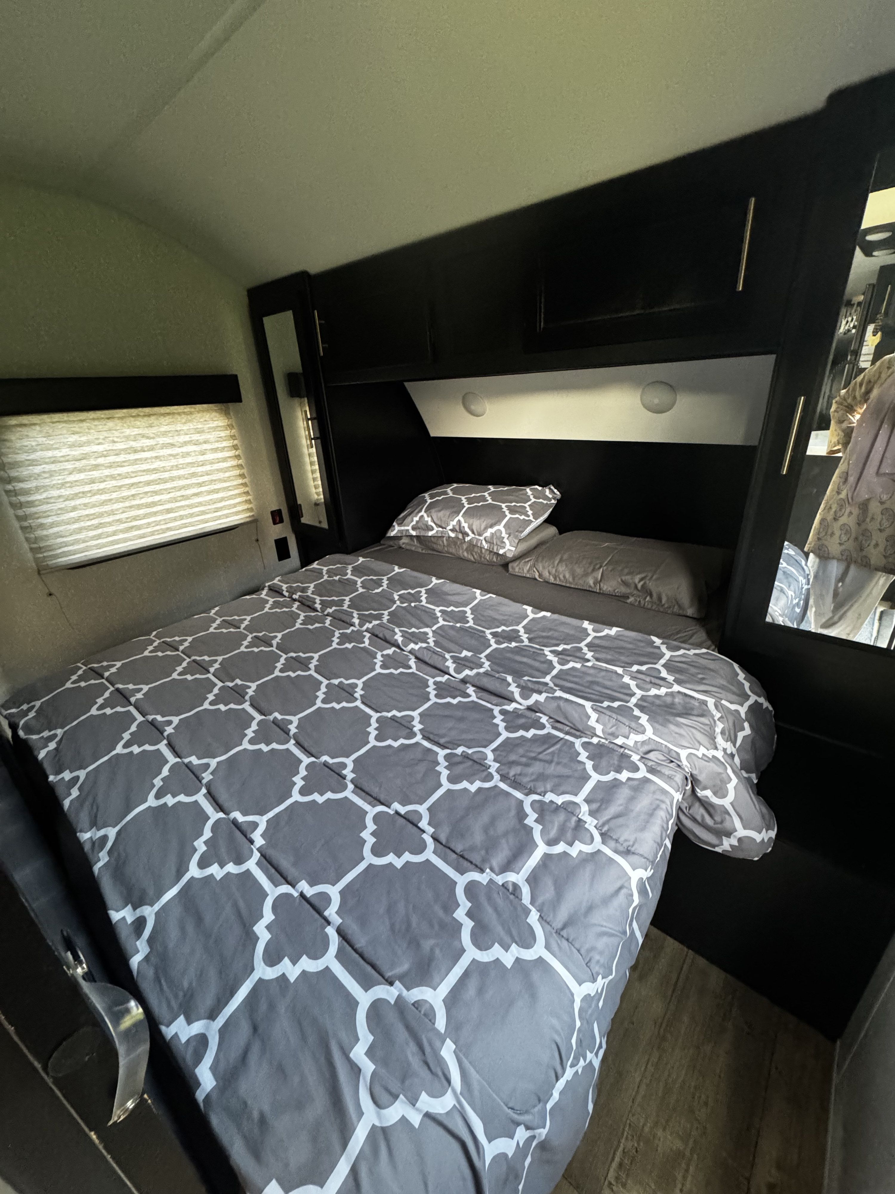 Cozy RV rental bedroom with gray patterned comforter, built-in storage, a window, and wood-look flooring.. Forest River Cherokee Grey Wolf 2021