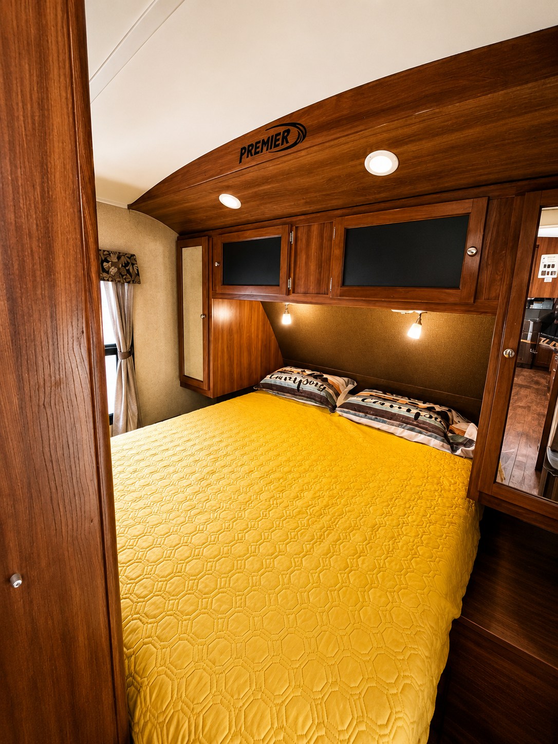 Step into this cozy RV rental bedroom. It features warm wooden decor, a bright yellow bedspread, and Premier amenities.. Keystone RV Bullet Ultra Lite 2013