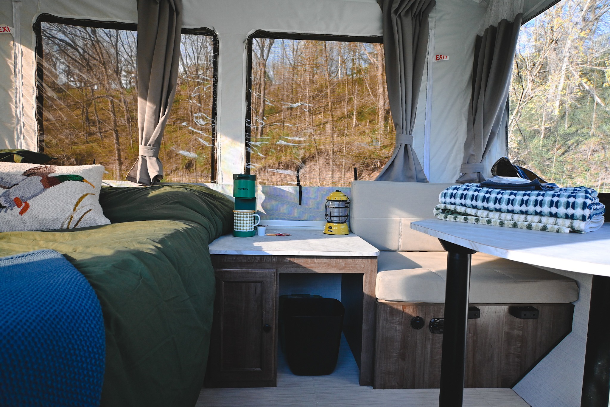 Inviting RV rental interior: bed, dining area, and forest views. A cozy escape for your next road trip adventure.. Forest River Flagstaff OTG 2024
