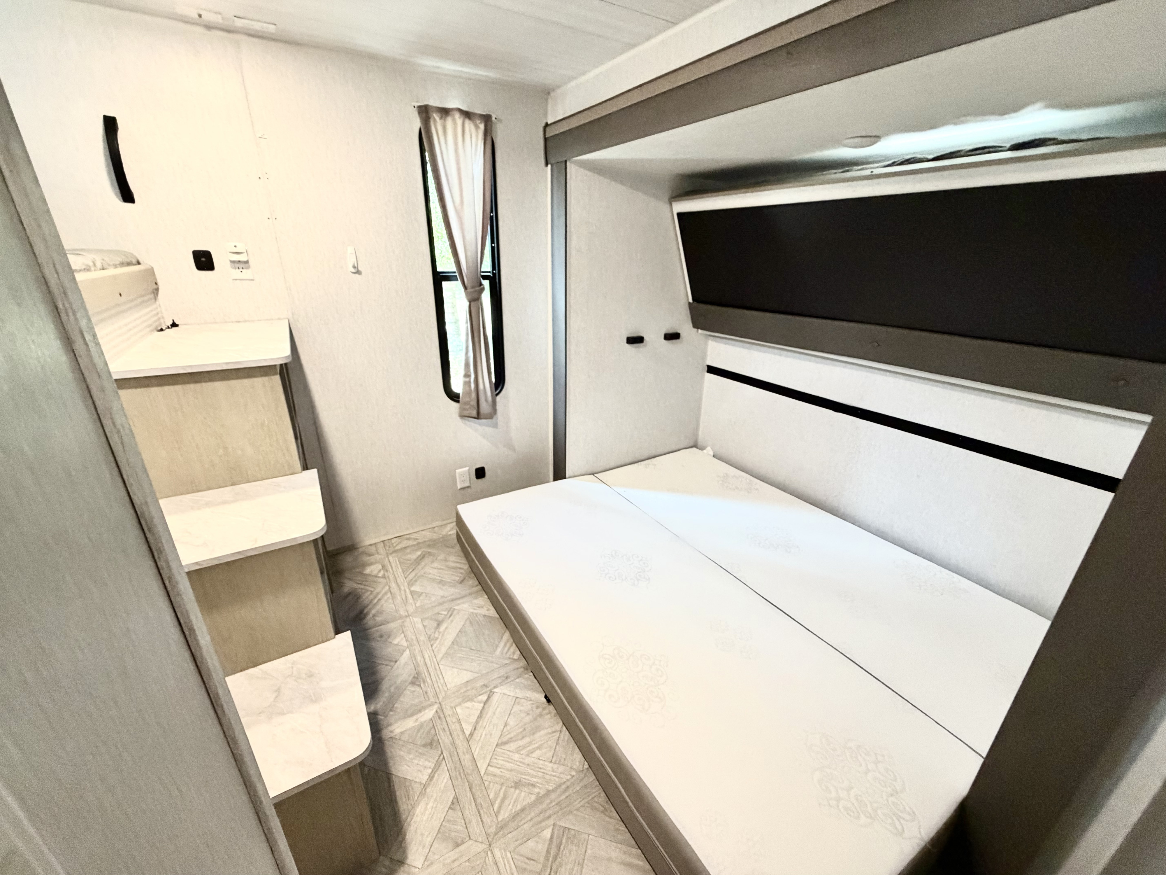 RV rental bedroom: A compact camper space featuring a convertible bed, bunk access stairs, and a window for comfort.. Forest River Salem Platinum 2024