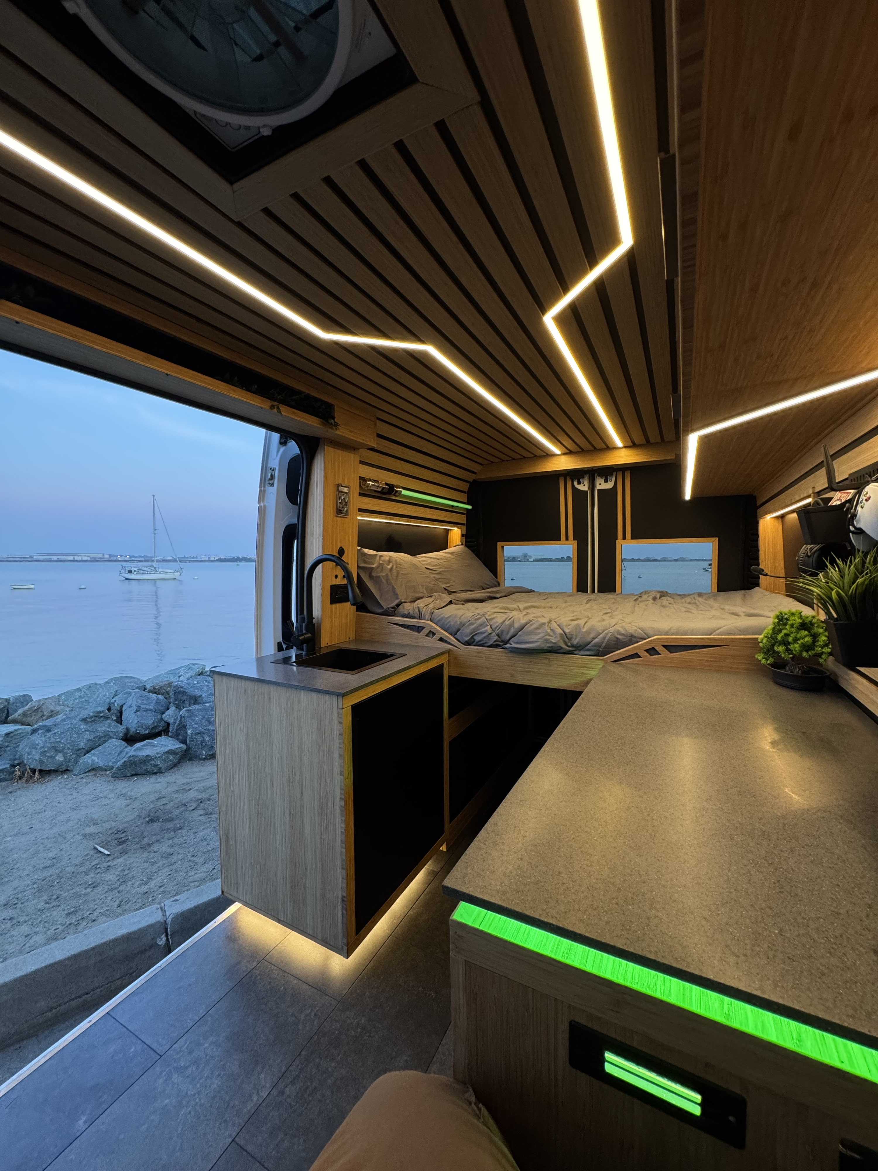 Modern RV rental interior with sleek LED lighting, ocean views, a comfy bed, and kitchenette. Experience mobile living luxury!. Dodge Ram 1500 2019