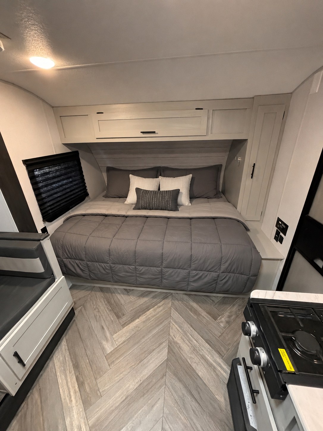 Cozy rv rental bedroom with overhead storage, a window, and adjacent kitchen/seating area.. Forest River Wildwood FSX 2022