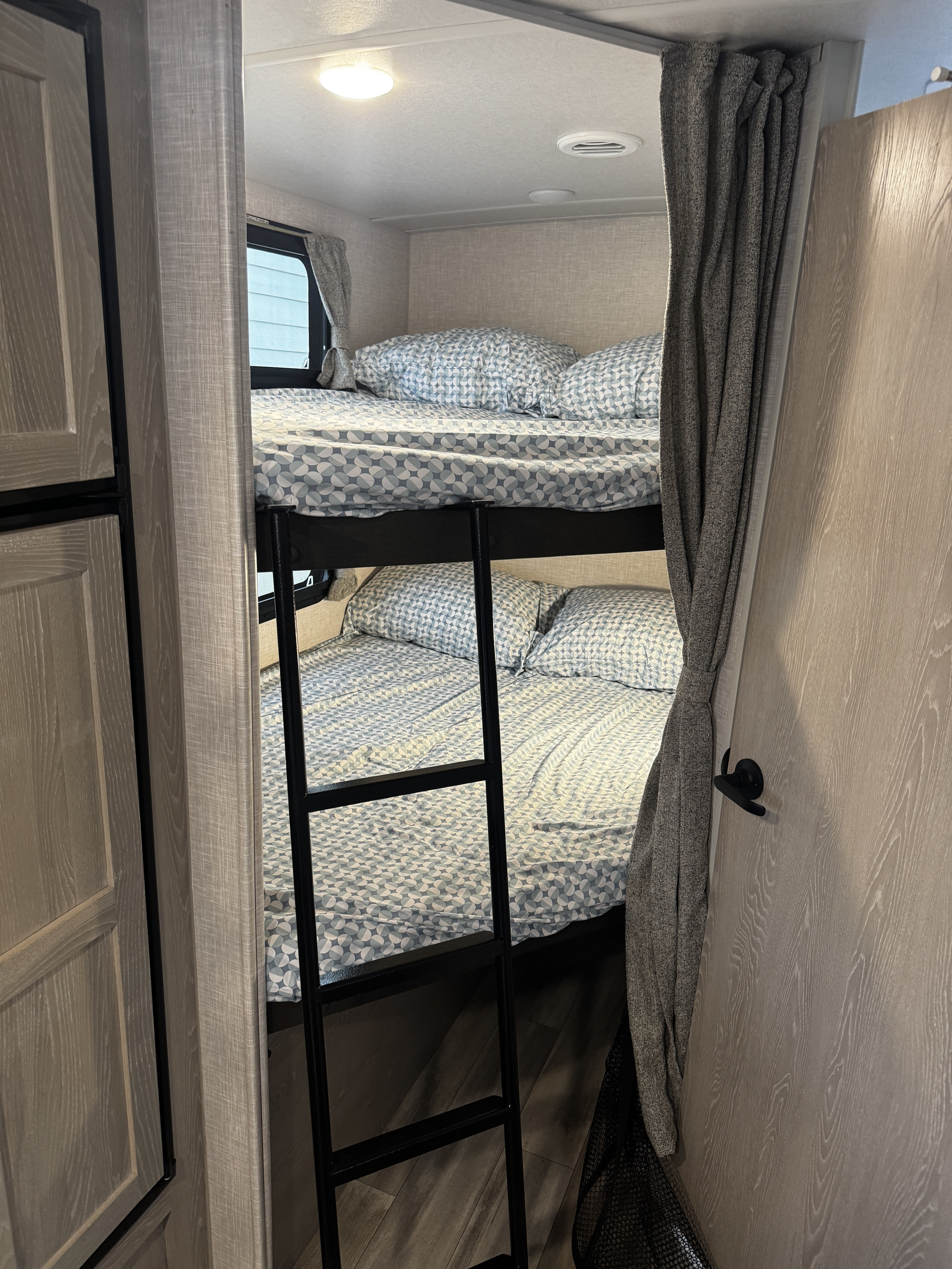 Cozy bunk beds with light patterned bedding and a ladder in an RV rental sleeping area.. Forest River Flagstaff Micro Lite 2022