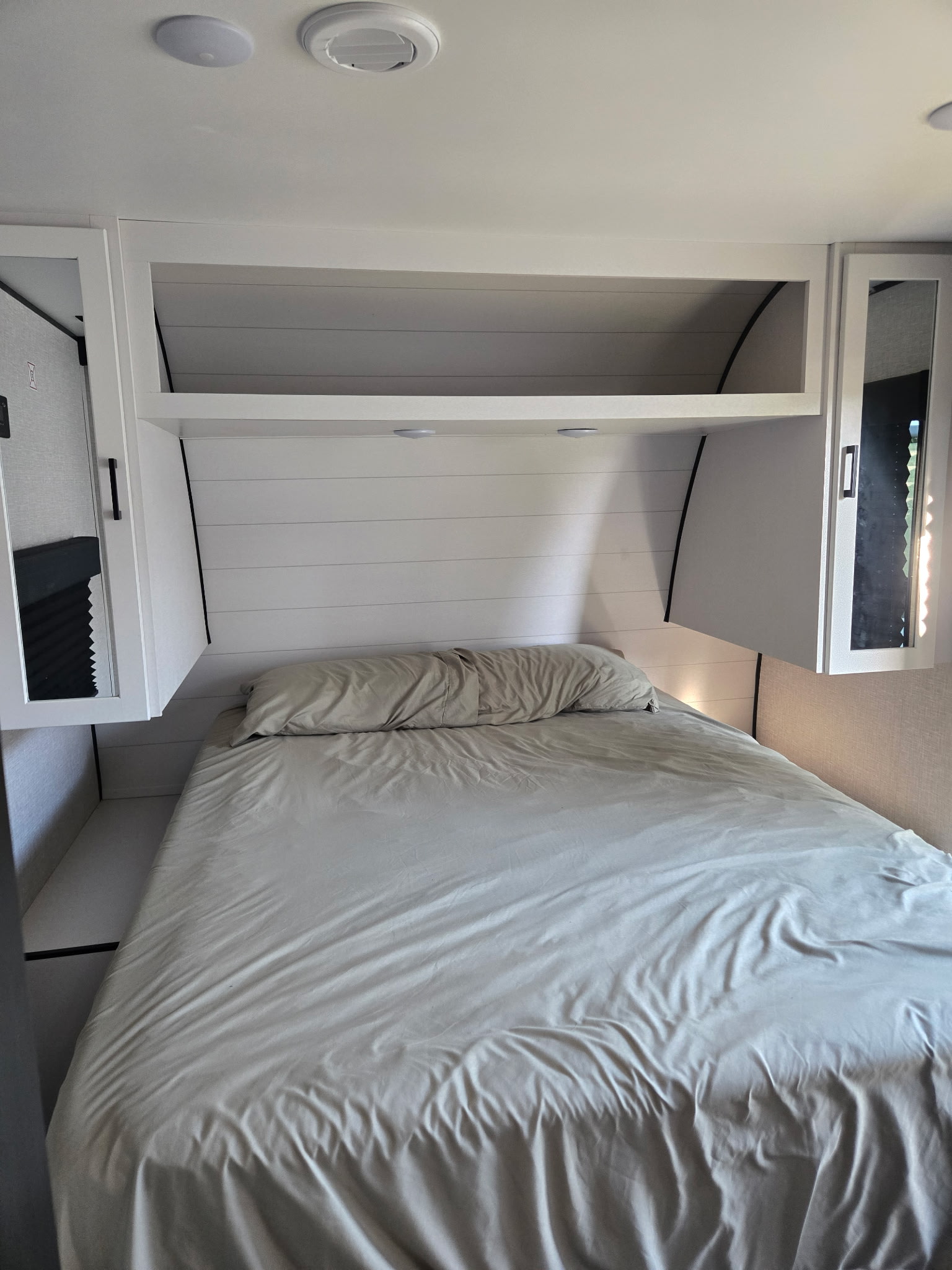 Clean RV rental bedroom with a bed, overhead storage, and a modern shiplap headboard for guests.. Jayco Jay Flight SLX 2025
