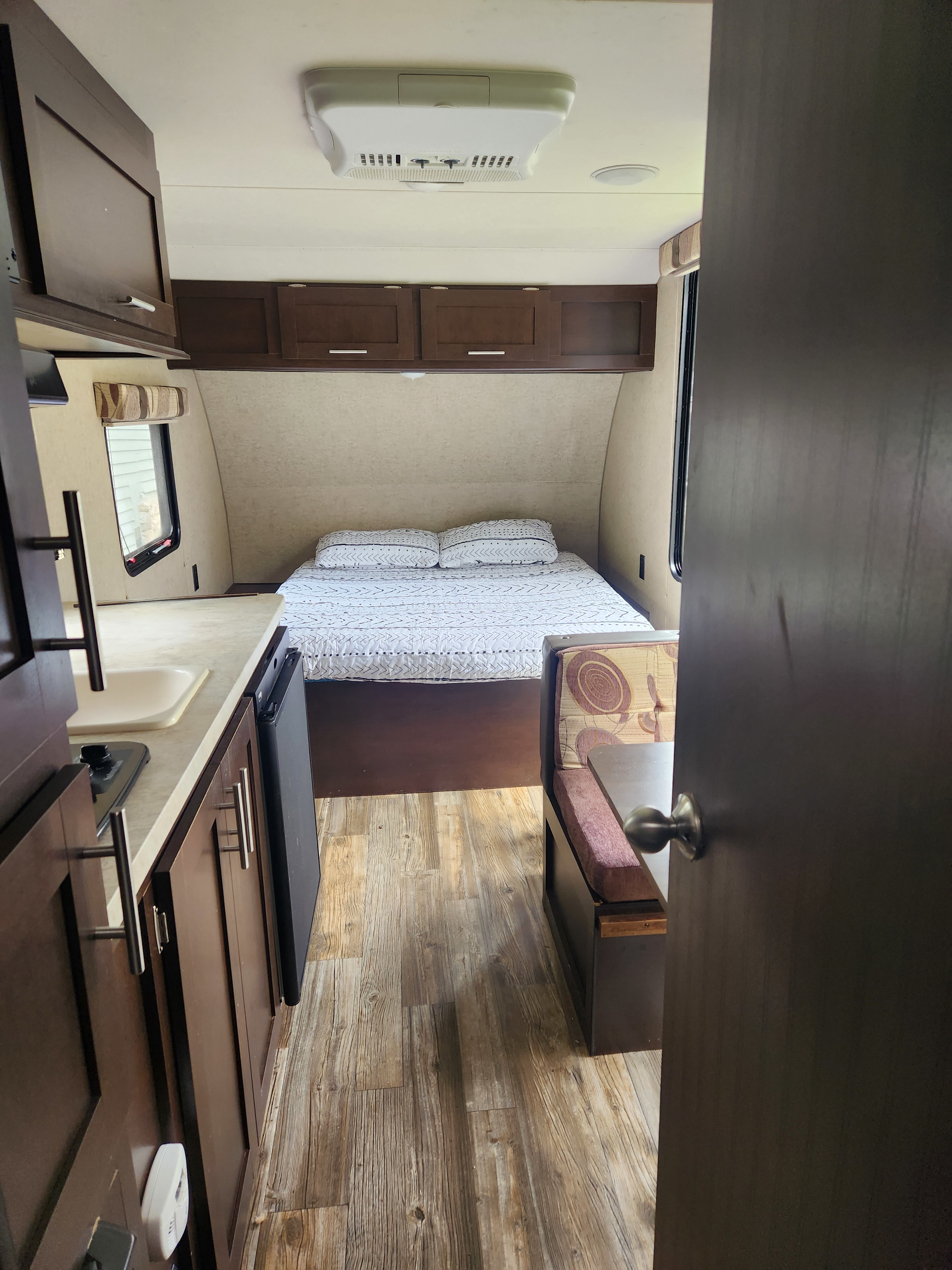 Interior view of an rv rental: a cozy bed, compact kitchen counter with appliances, and a small dinette area.. Forest River Cherokee Wolf Pup 2017