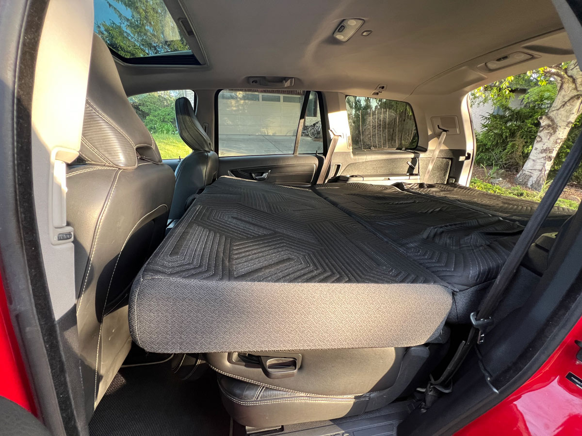 Car's rear seats folded flat with a mattress, creating a sleeping area. A practical setup for car camping or an rv rental adventure.. Volvo xc90 2014