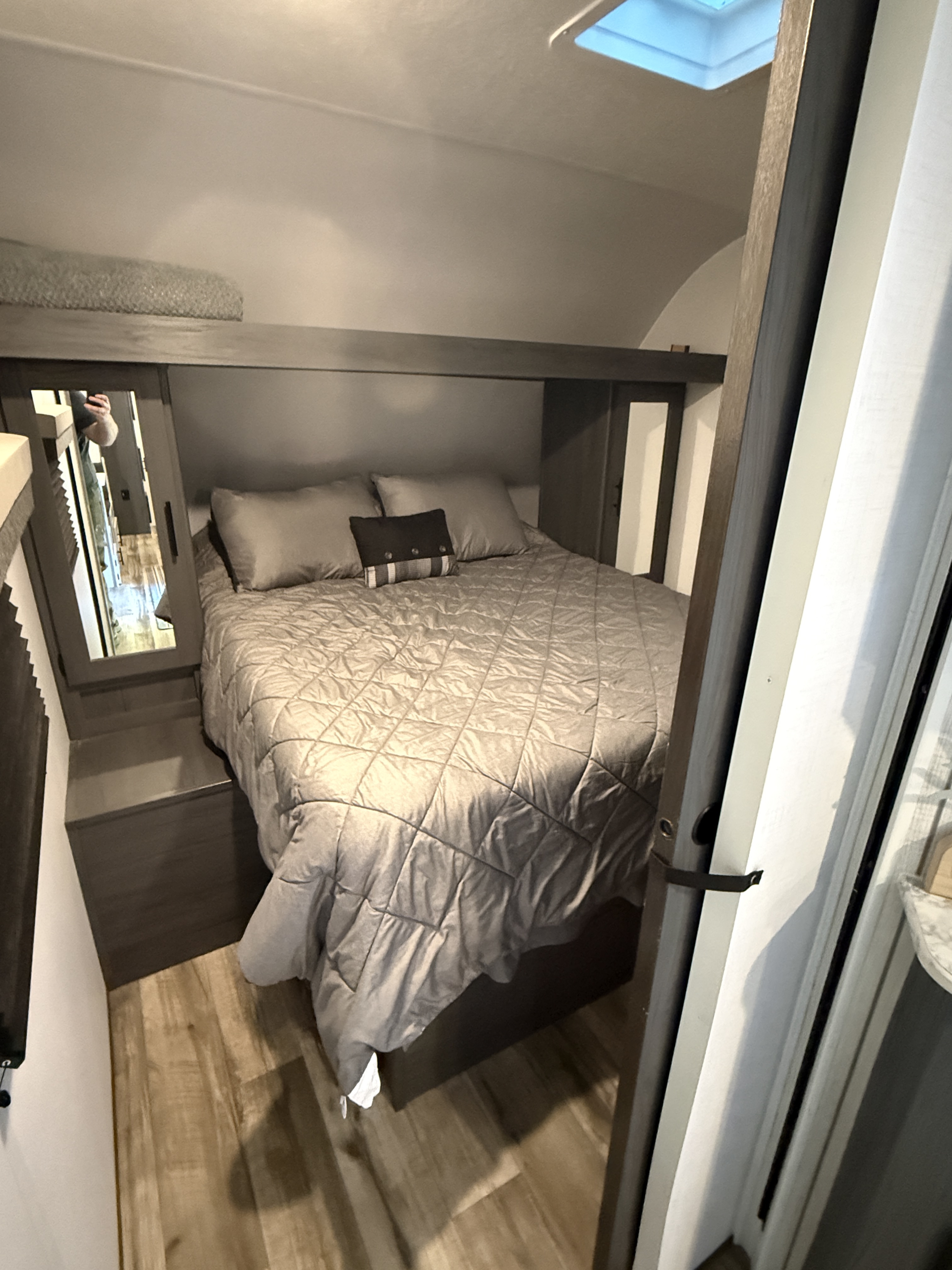 Cozy RV rental bedroom with a queen bed, quilted comforter, overhead storage, and wood-look flooring.. Aspen Trail 29tb 2026