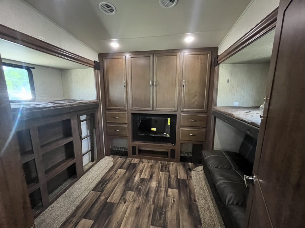 Experience comfort in this RV rental bunkhouse: central TV, ample storage, and cozy bunk beds on both sides for families.. Forest River Sandpiper 2020