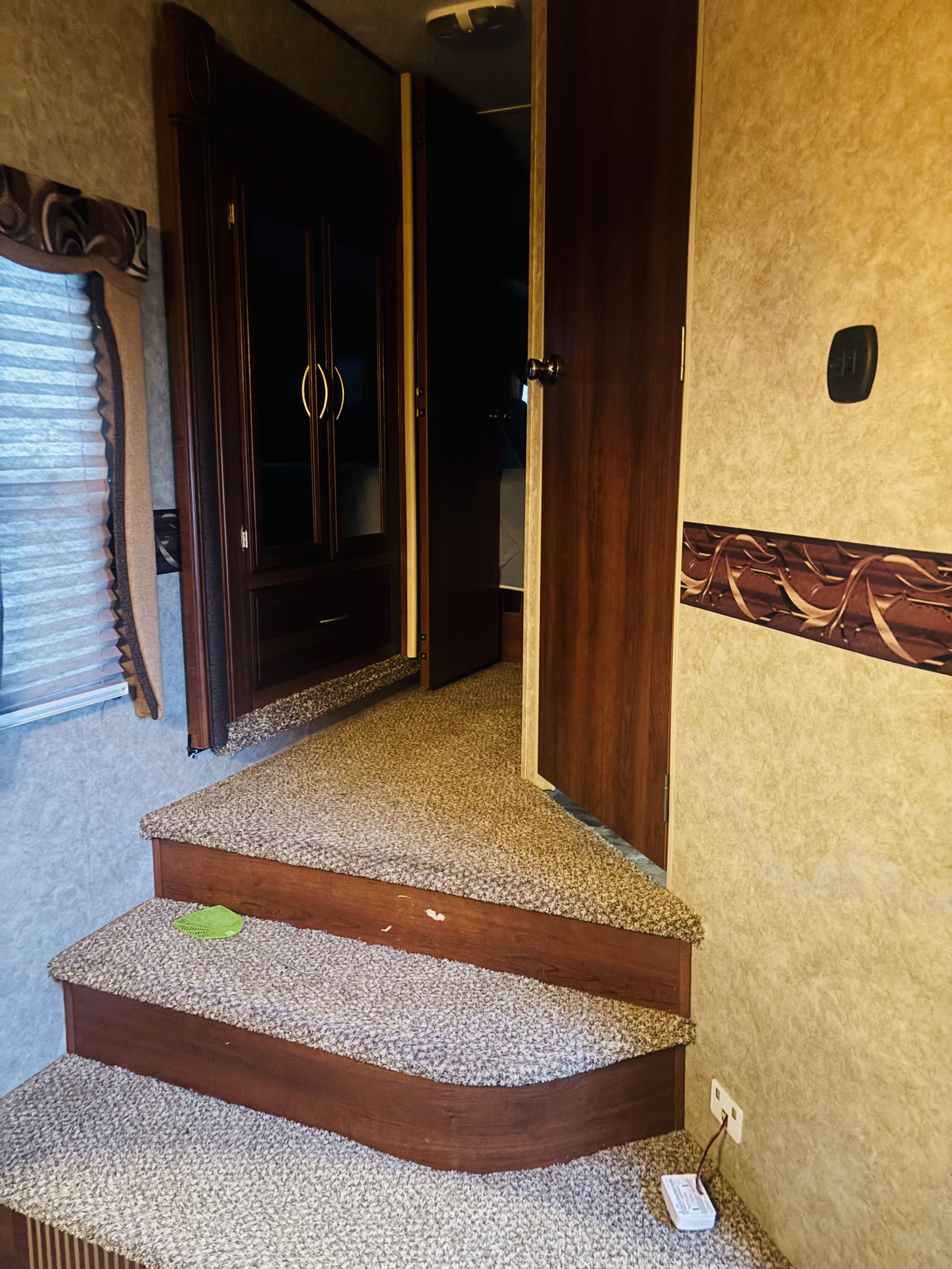 RV rental interior with carpeted steps, dark wood details, and open doorways, giving a view into the living space.. Forest River 360bhs 2013