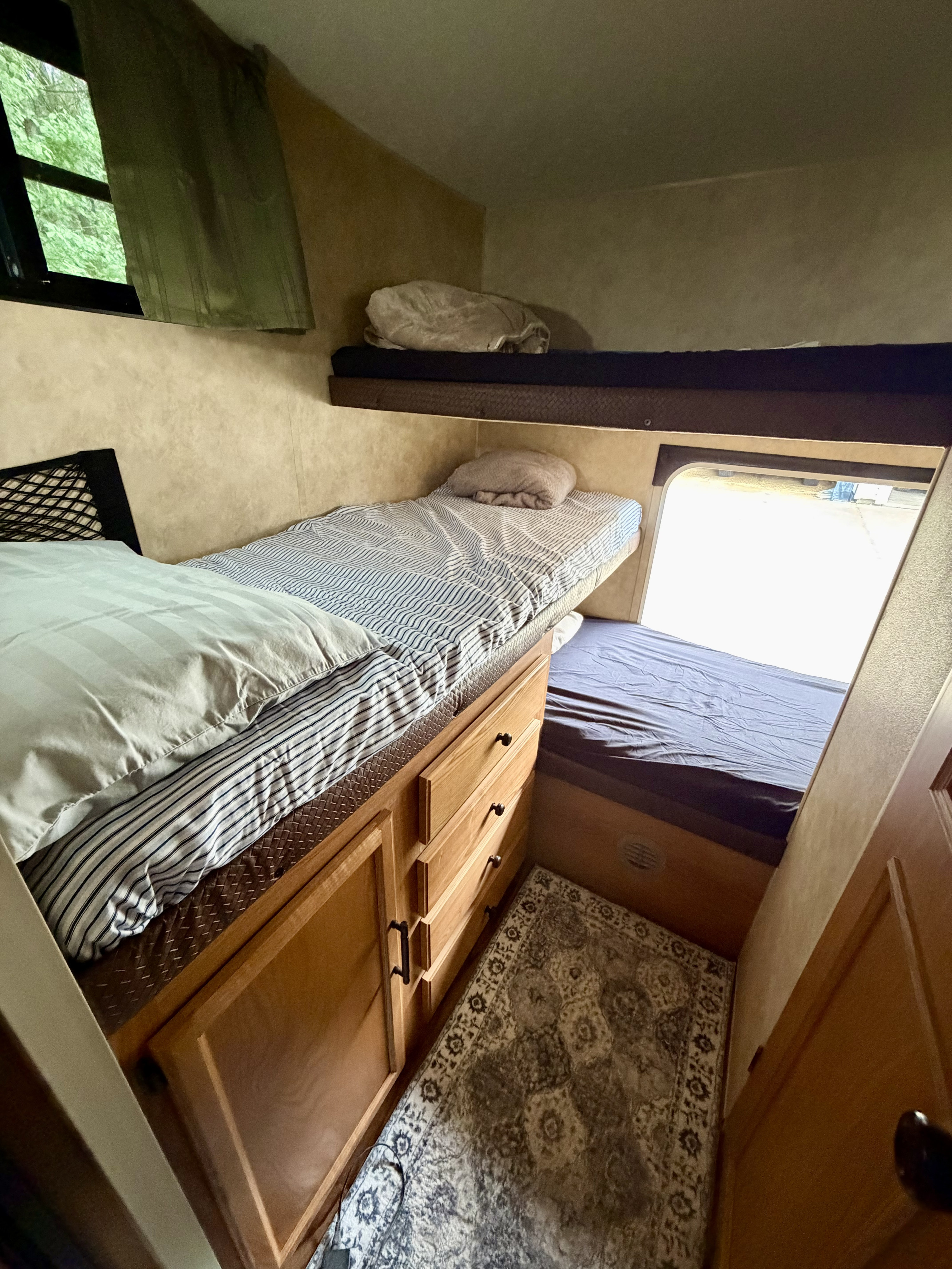 RV rental interior featuring comfortable bunk beds, a window, wooden dresser, and a patterned rug, offering compact sleeping.. Sportsmen Sportsmen Trailer 2008