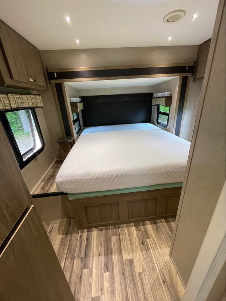 Spacious RV rental bedroom featuring a queen bed in a slide-out, wood-look floor, and windows. Ready for your trip.. Isata 3 2017
