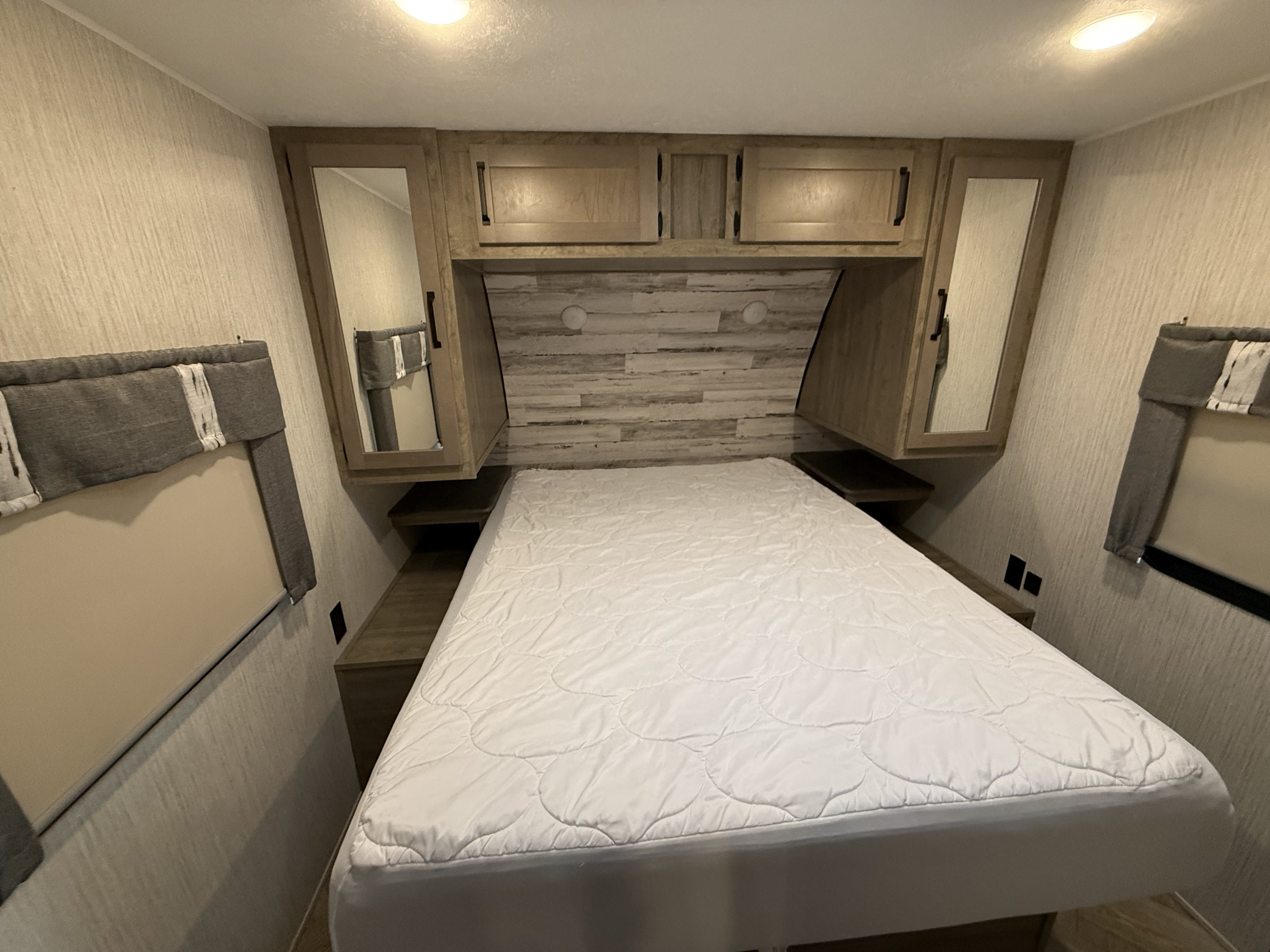 Cozy RV rental bedroom featuring a comfortable bed, built-in overhead cabinets, side shelves, and window blinds.. Forest River Palomino Puma 2022