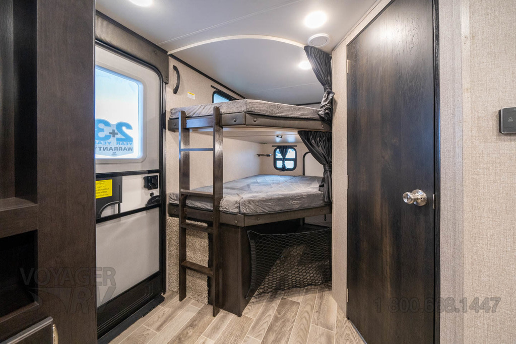 RV rental interior showcasing bunk beds, ladder, window, and storage net – a compact sleeping space for trips.. Jayco Jay Feather 2023