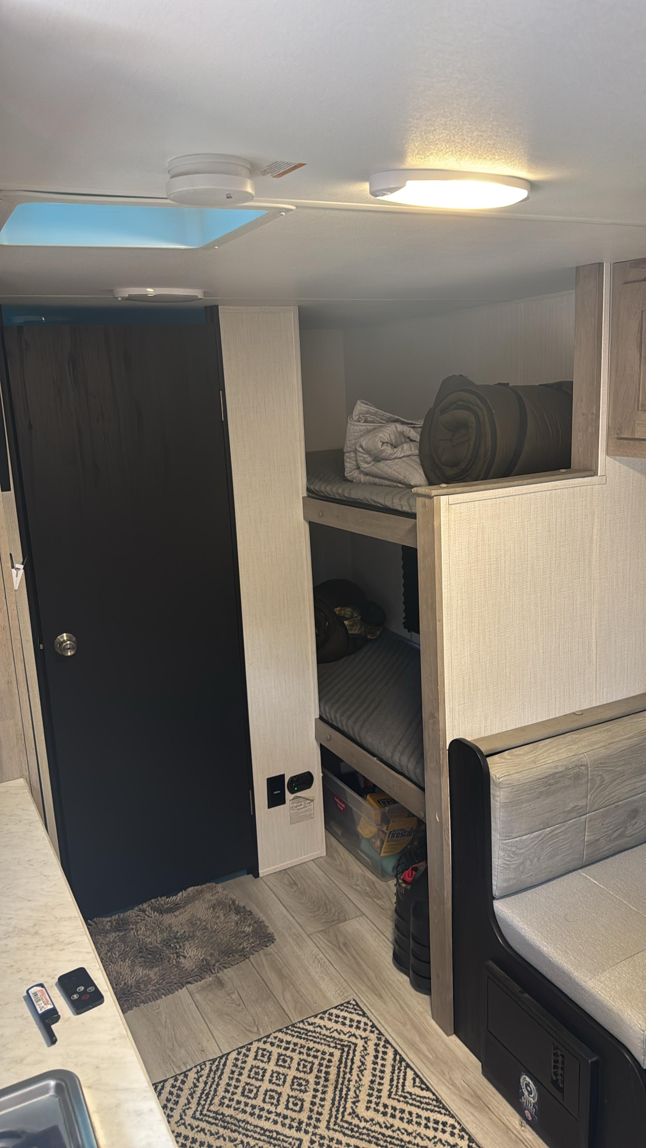 This RV rental interior features cozy bunk beds, a dinette, and a compact kitchen counter, perfect for family travel.. Heartland RVs Prowler Lynx 2024