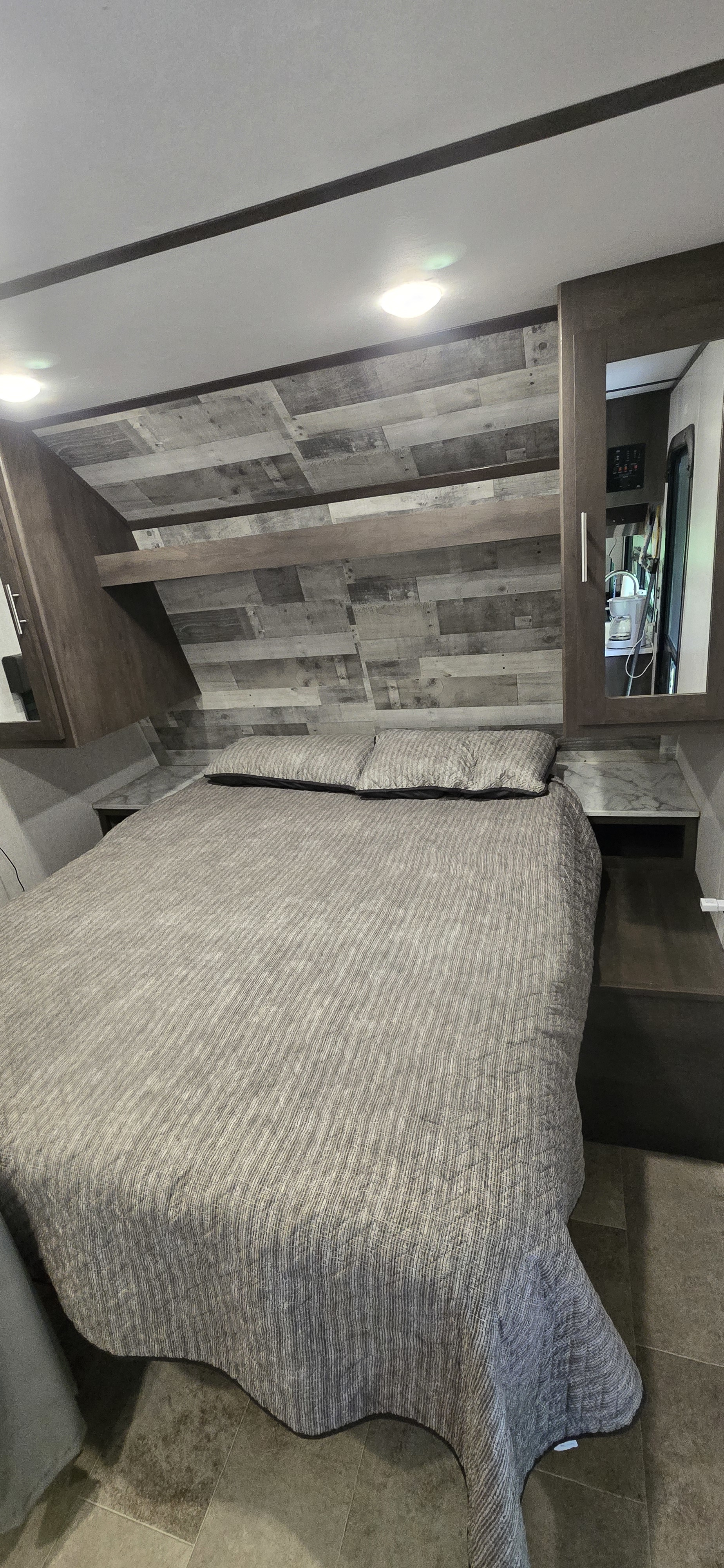 Inviting rv rental bedroom showcases a comfortable bed, textured headboard, and mirrored storage. Perfect for your trip!. Dutchmen Coleman Lantern LT 2021