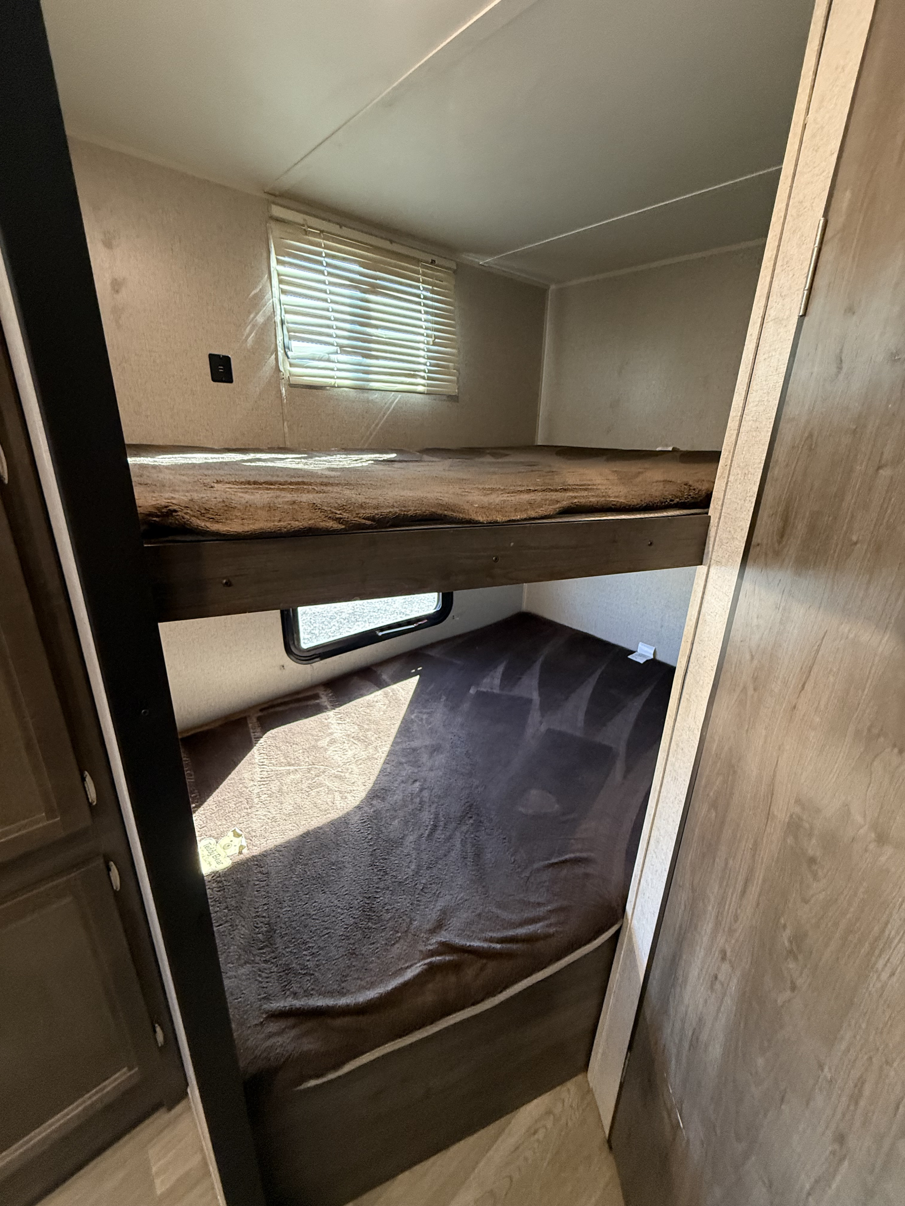 Cozy bunk beds with windows and power outlets inside an RV rental, offering comfortable sleeping arrangements for your trip.. Coleman 262BH 2019