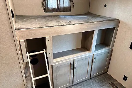Inside an RV rental: a modern bunk bed with a ladder and built-in storage cabinets, perfect for family adventures.. Forest River Aurora Aurora 2023