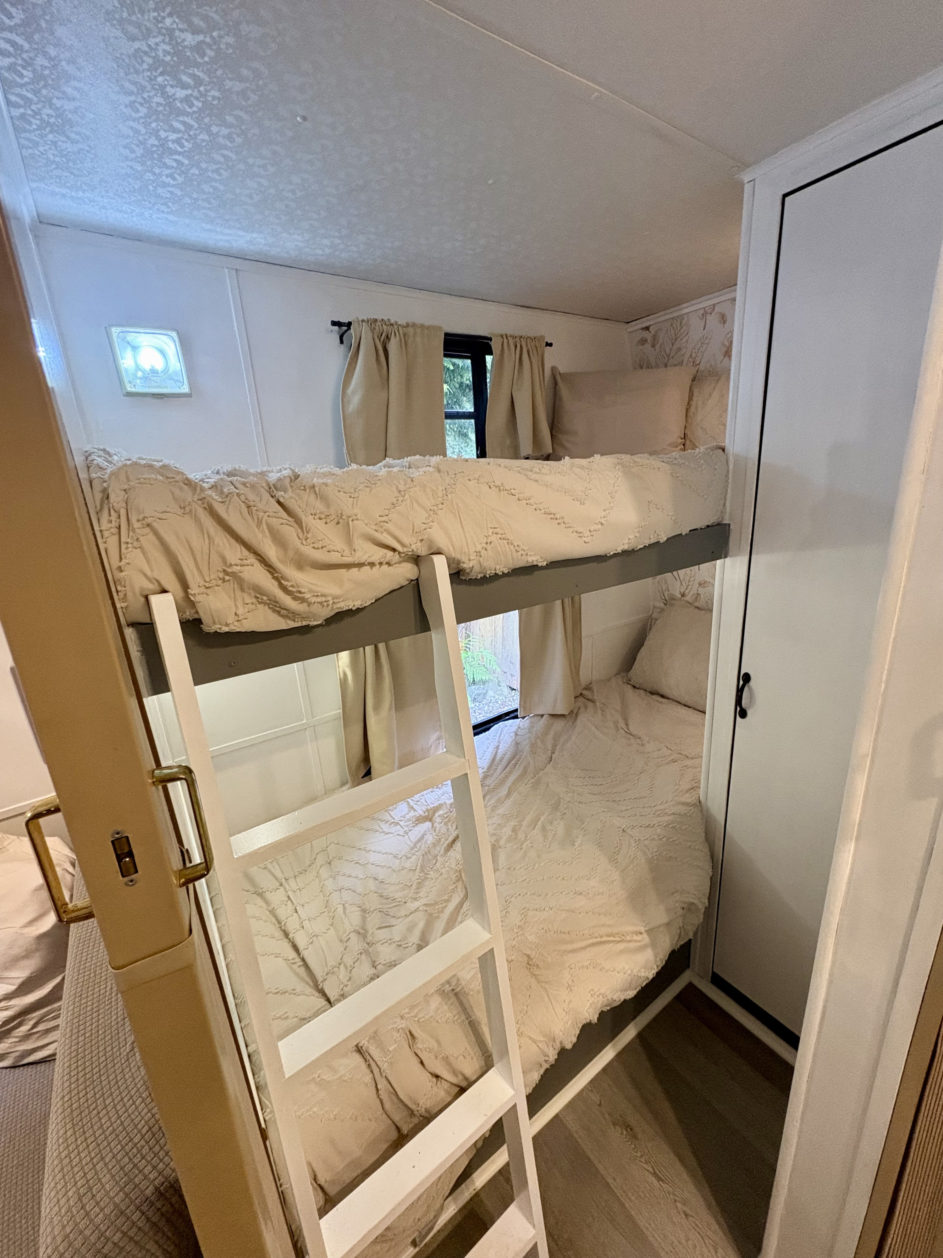 This RV rental features cozy bunk beds with cream bedding, a ladder, and a white closet for compact comfort.. Dutchmen Classic 1993