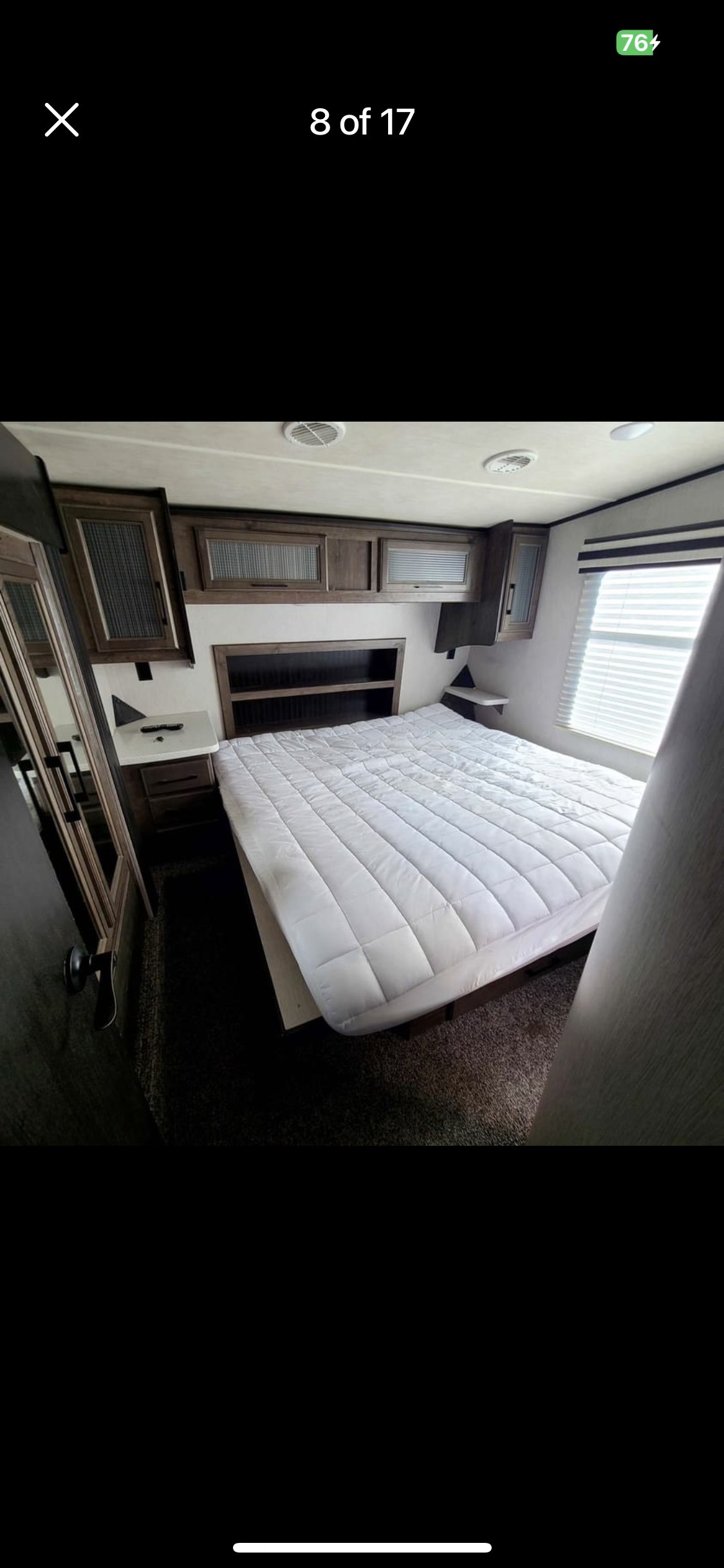 RV rental bedroom with a large bed, built-in storage cabinets, nightstand, and window blinds.. Heartland Cyclone 2018