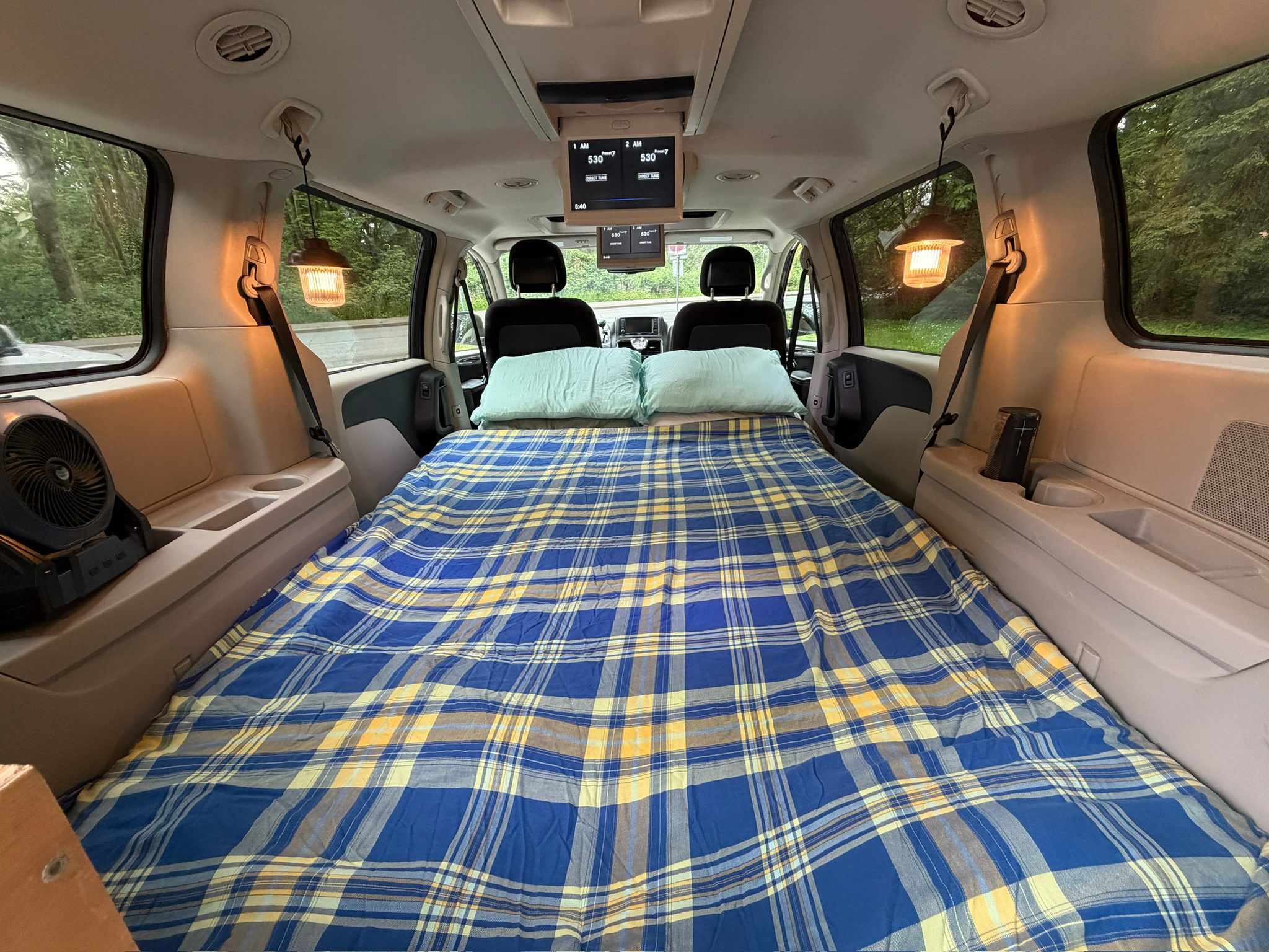 RV rental van conversion: comfy bed, pillows, fan, and lanterns inside for a cozy camp setup.. Chrysler Town & Country 2014
