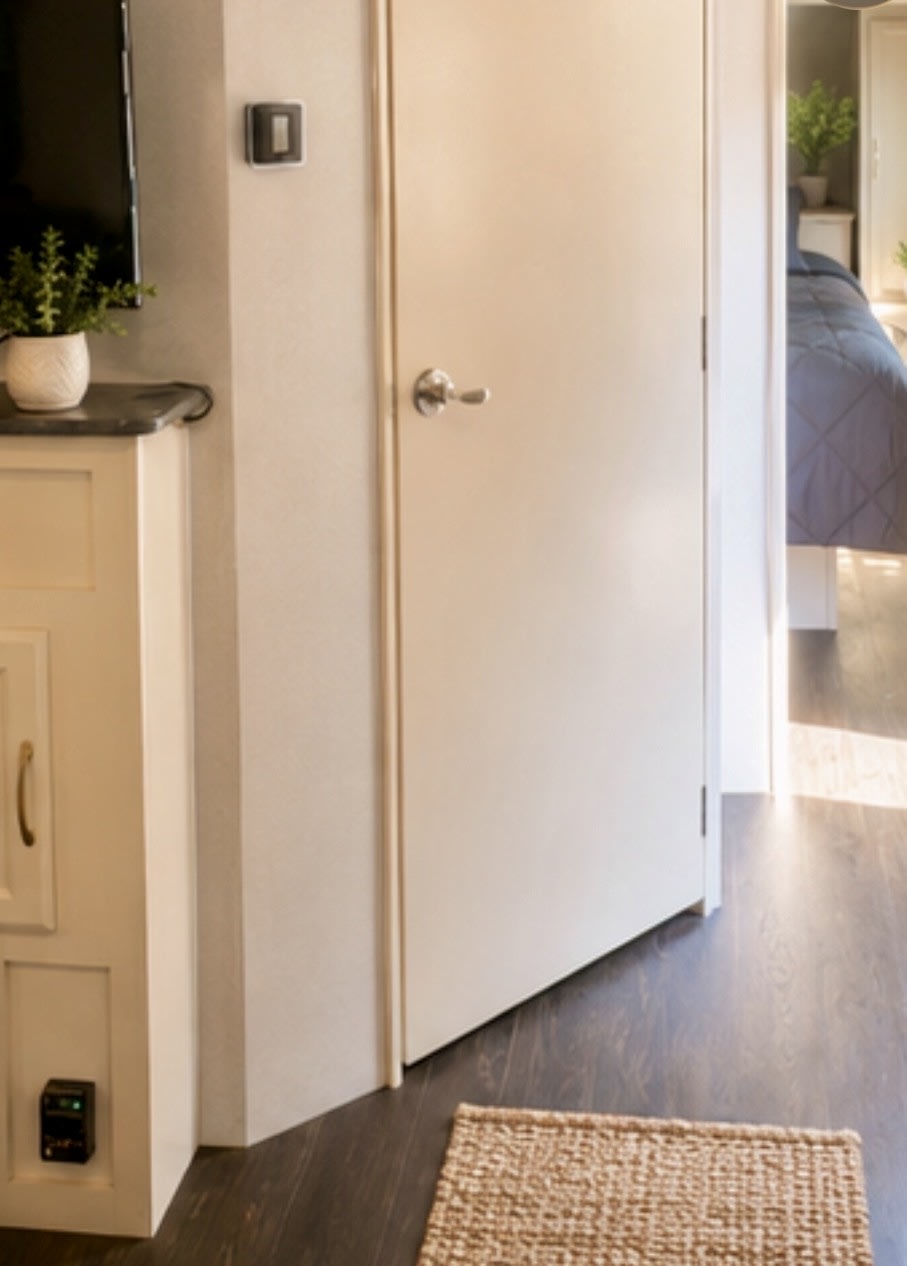 RV rental interior: A door opens to a cozy bedroom. Features include dark wood flooring, a plant, and a small rug.. Winnebago 2500RL 2018