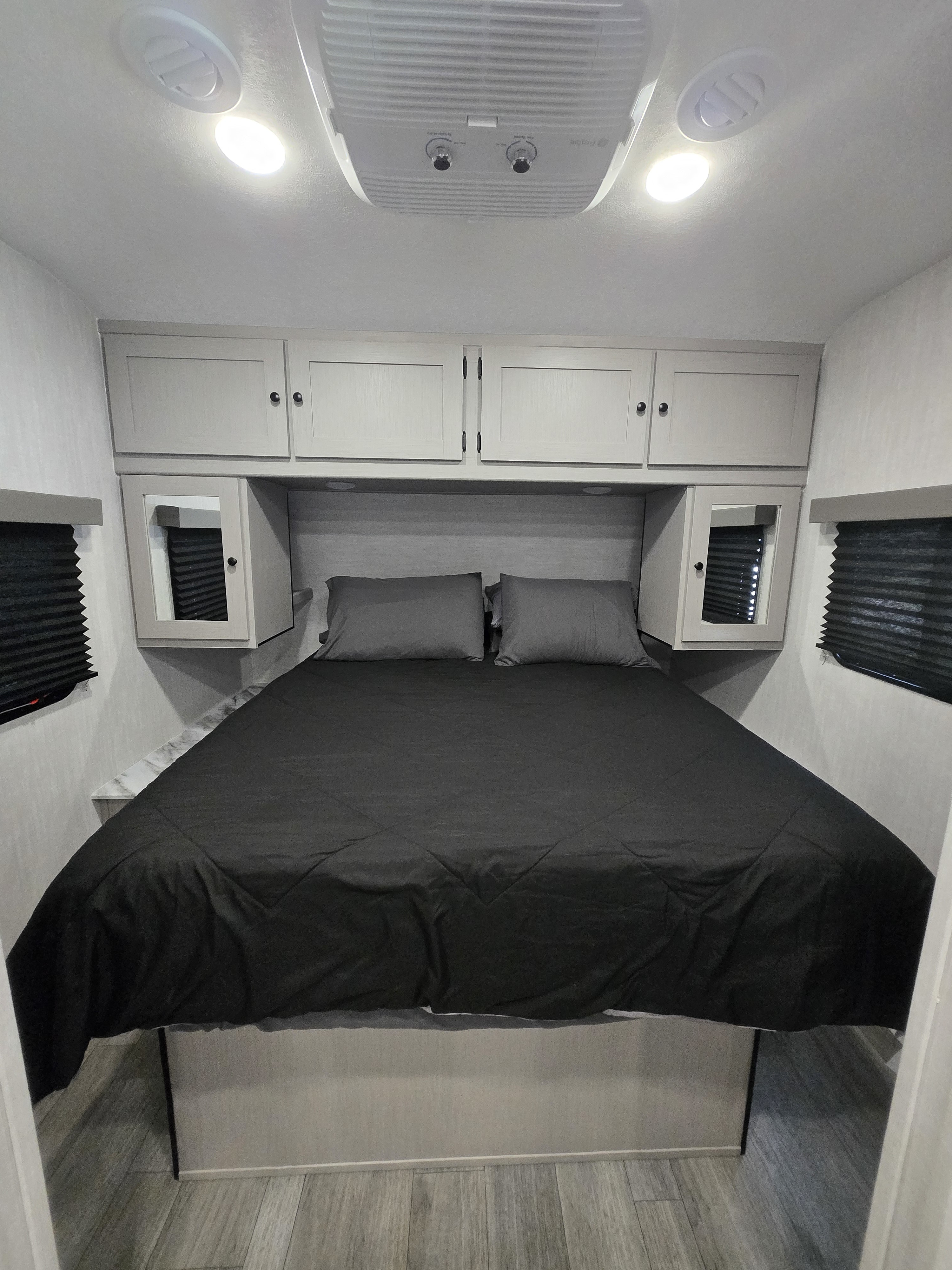 Comfortable RV rental bedroom featuring a queen bed, modern overhead storage, and ceiling AC unit.. Coachmen Apex X 2025