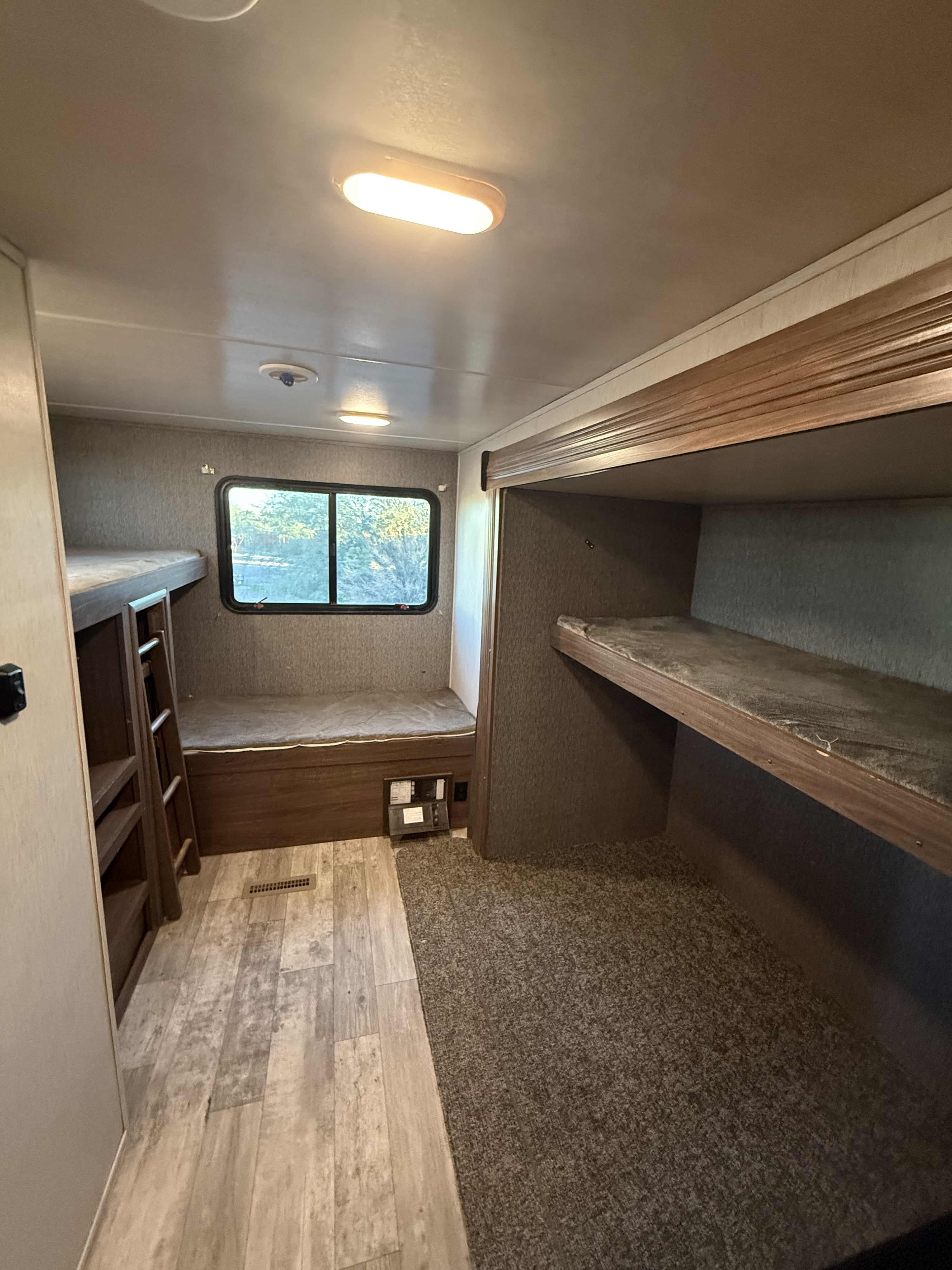 RV rental bunkhouse interior with wood-look flooring transitioning to carpet, featuring bunk beds and a window.. Pioneer DS320 2019